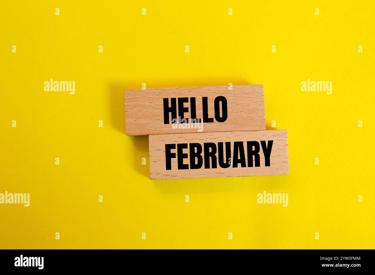 Bonjour février message écrit sur des blocs de bois avec fond jaune. Symbole conceptuel bonjour février. Copier l'espace. Banque D'Images
