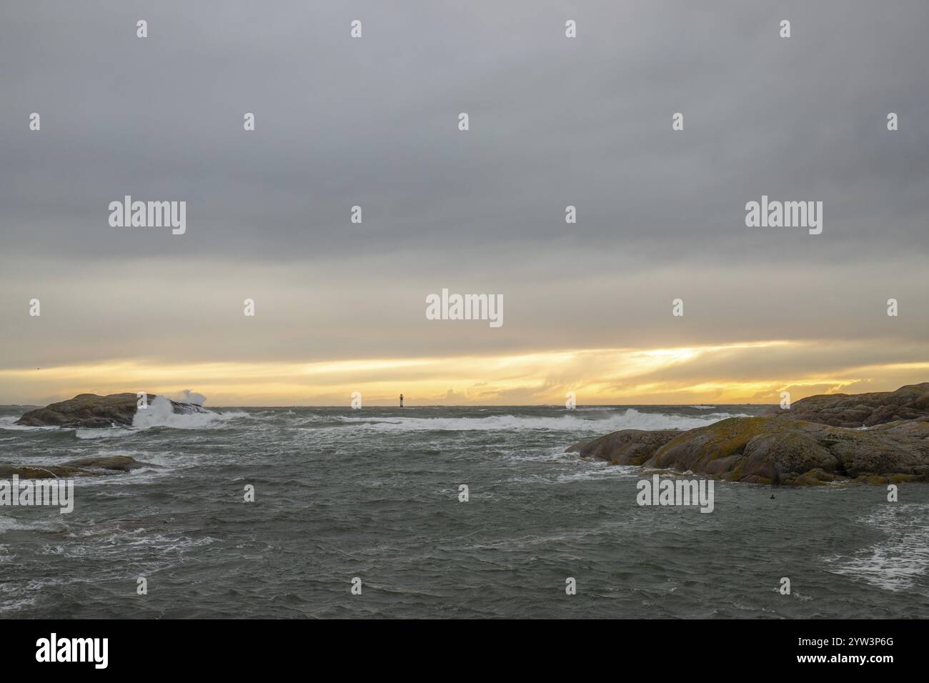 Un phare se dresse dans la tempête. Mer sauvage dans la soirée. Coucher de soleil sur une côte avec de nombreux rochers dans la mer du Nord. Paysage marin en Suède, Scandinavie Banque D'Images