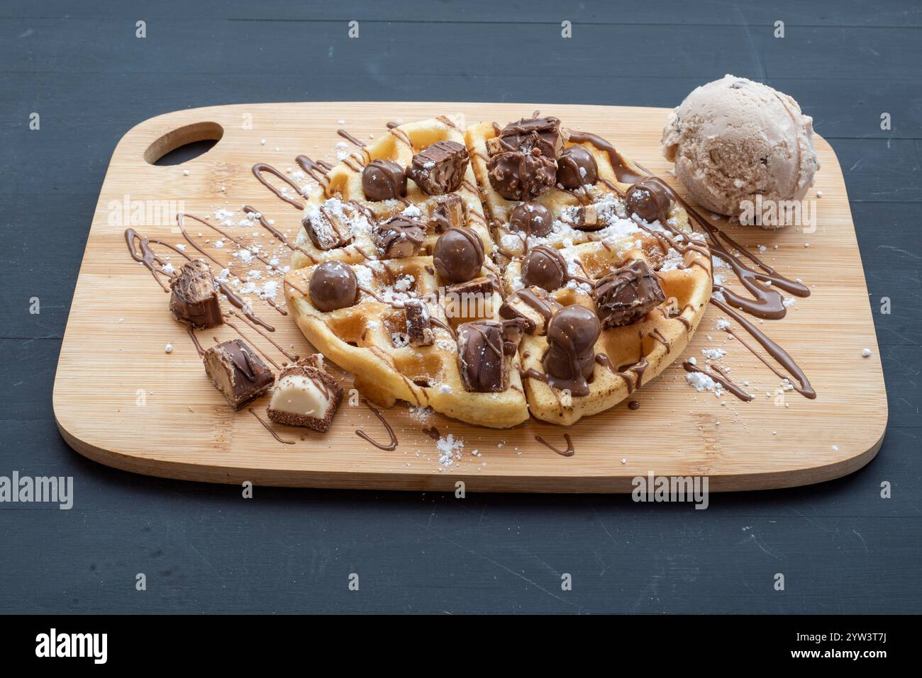 Délicieuse gaufre au chocolat garnie de morceaux de kinder bueno et malteasers et servie avec de la crème glacée et un filet de sauce au chocolat Banque D'Images