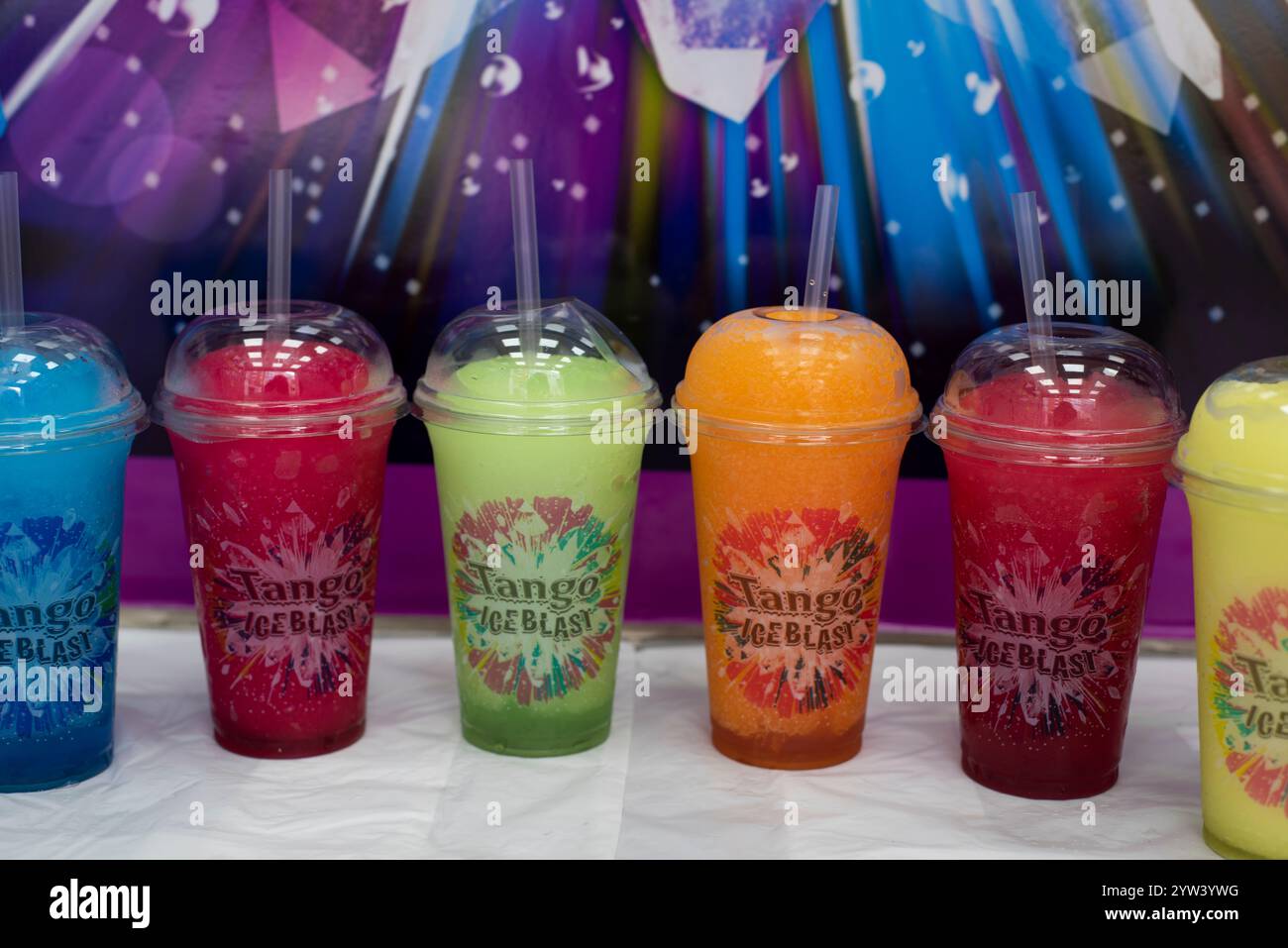 Les saveurs Tango Ice Blast sélectionnées dans des tasses en plastique sortent devant un fond coloré Blast Banque D'Images