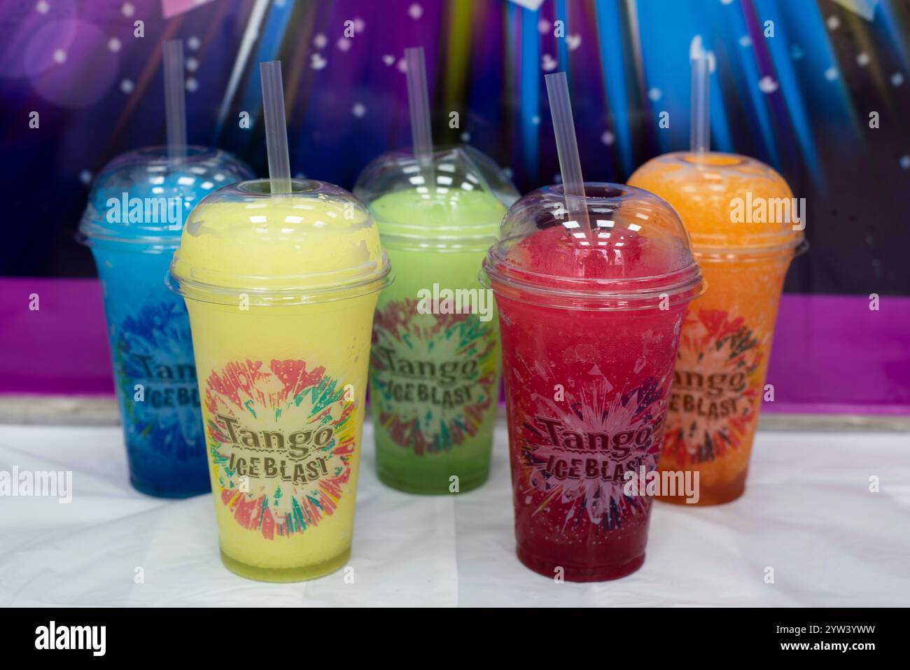 Les saveurs Tango Ice Blast sélectionnées dans des tasses en plastique sortent devant un fond coloré Blast Banque D'Images