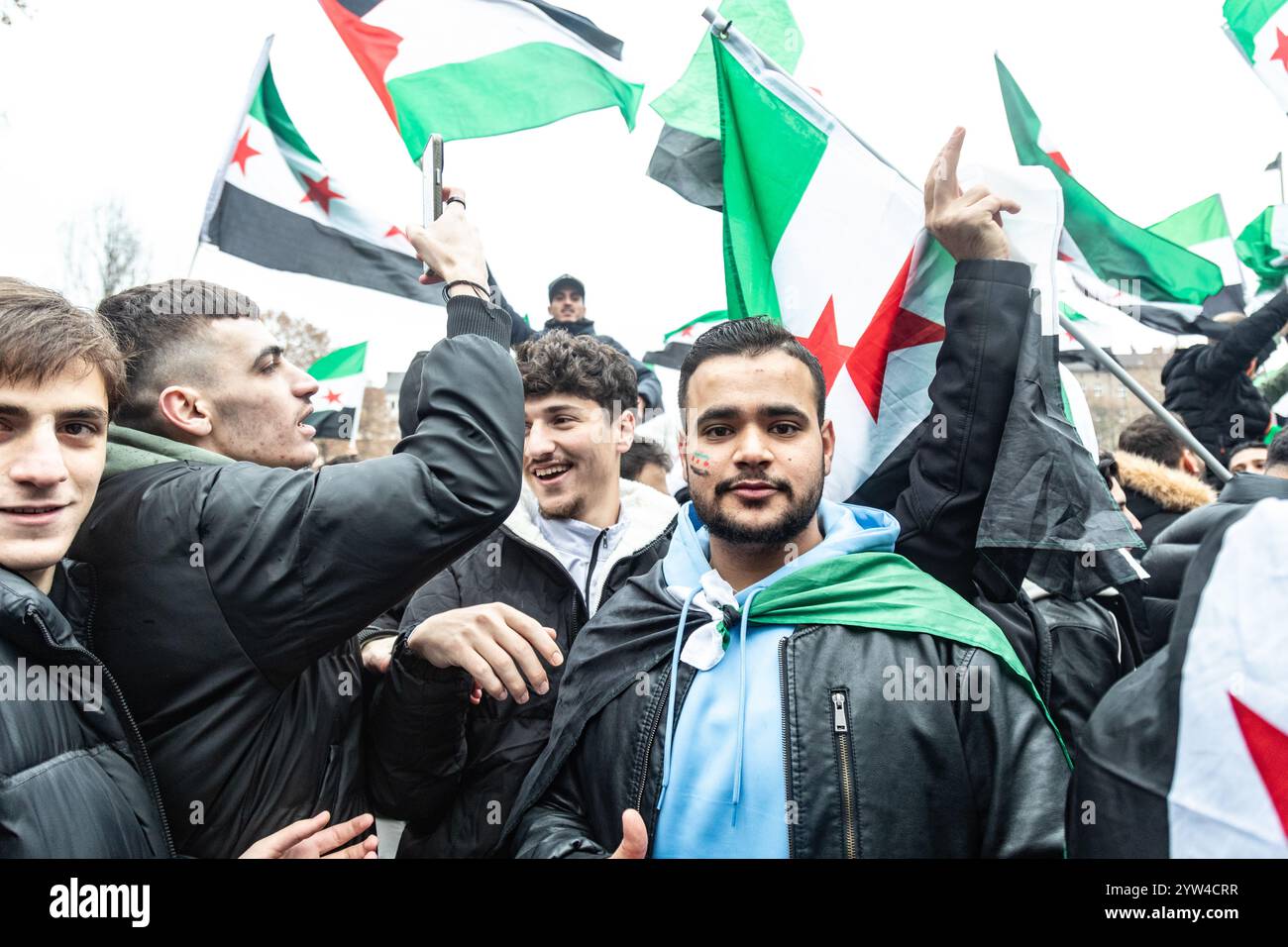 Les gens brandissent des drapeaux pendant la célébration. Les Syriens vivant à Berlin célèbrent la chute du régime Assad après une guerre civile depuis 2011. Banque D'Images