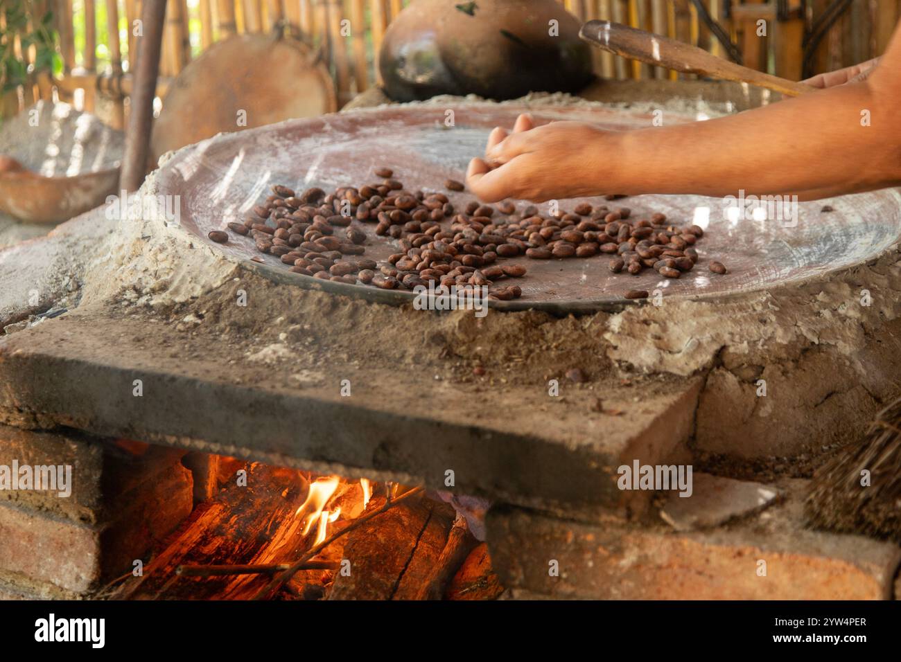 Une femme à Oaxaca Mexique torréfiant des fèves de cacao sur un comal dans un poêle à bois. Banque D'Images