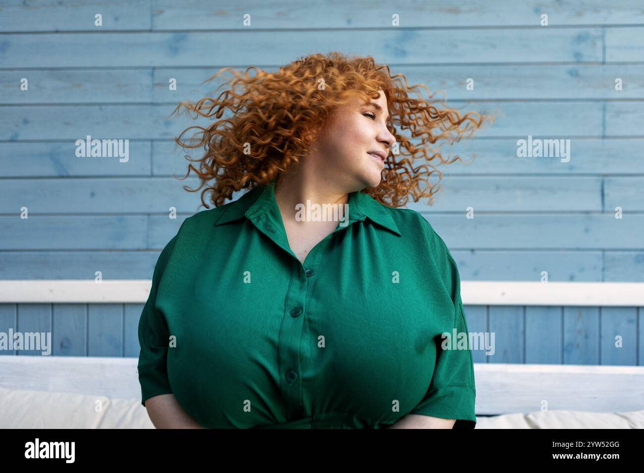 Belle femme Happy plus Size profitant de la vie, dansant et secouant les cheveux avec joie, confiance et émotions positives à l'extérieur sur fond bleu Banque D'Images