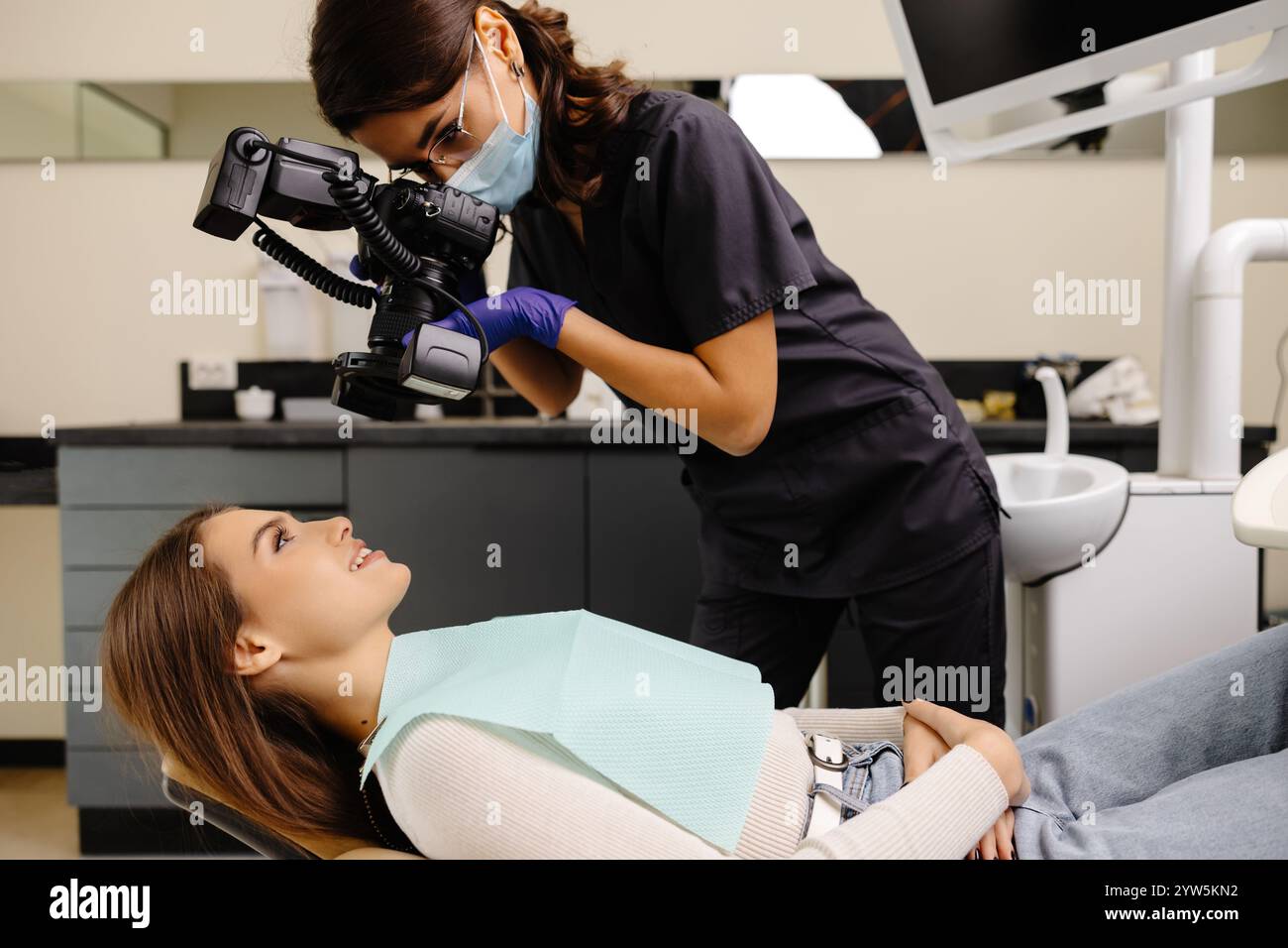 Femme dentiste photographiant avec un appareil photo professionnel le résultat de son travail en clinique. Banque D'Images