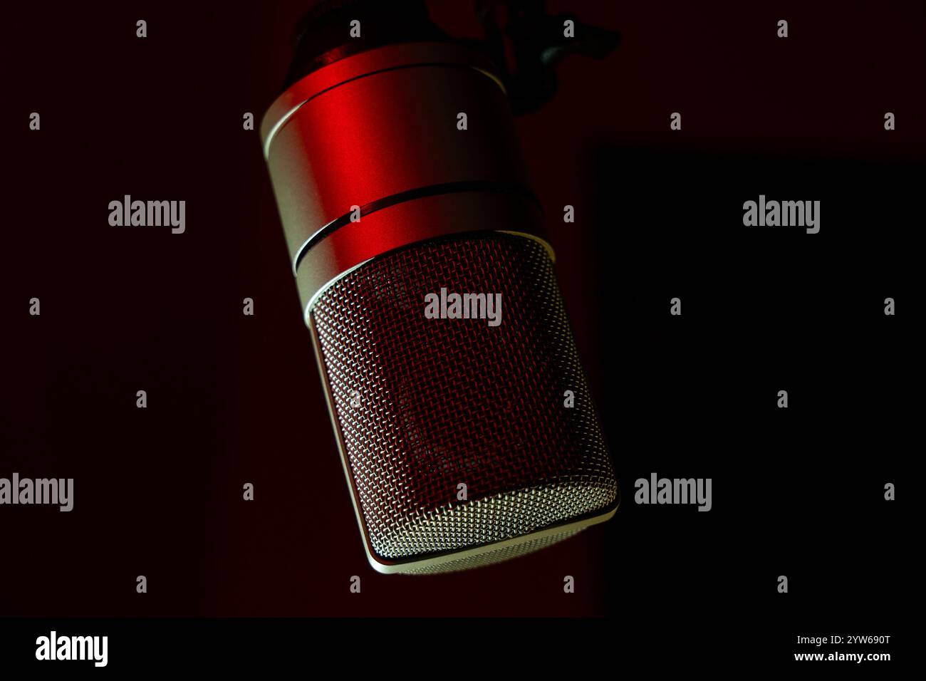 Microphone studio avec éclairage rouge sur fond sombre. Gros plan d'un microphone à condensateur professionnel pour l'enregistrement et le podcasting. Concept de production musicale et audio. Banque D'Images