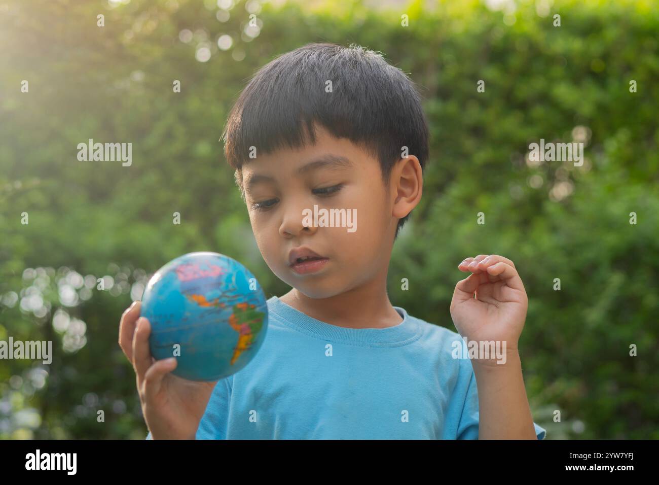 Image portrait de jouet de boule de planète de terre de jeu d'enfant asiatique sur fond de nature. Concept de jour de la Terre. Banque D'Images