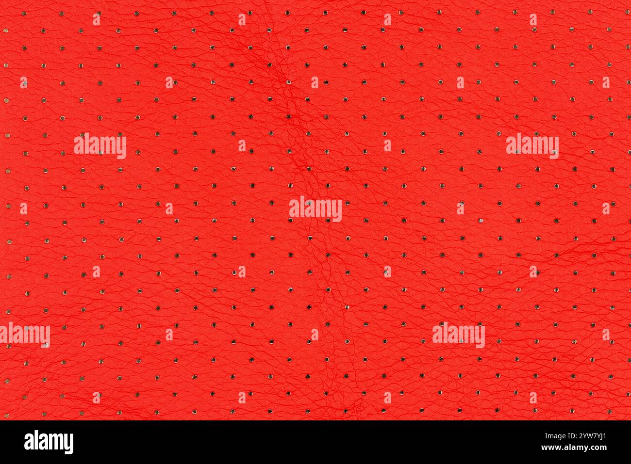 Cuir artificiel abstrait de couleur rouge vif avec petits points et motifs de trous pour le fond. Vue rapprochée de la surface respirante rouge éclatante Banque D'Images