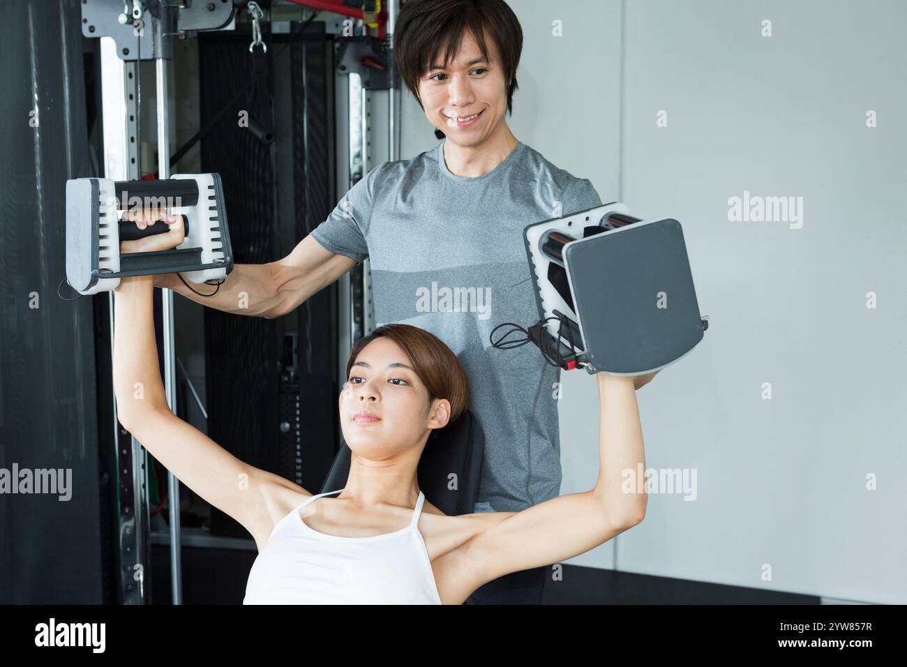 Jeune femme s'entraînant au gymnase avec entraîneur Banque D'Images