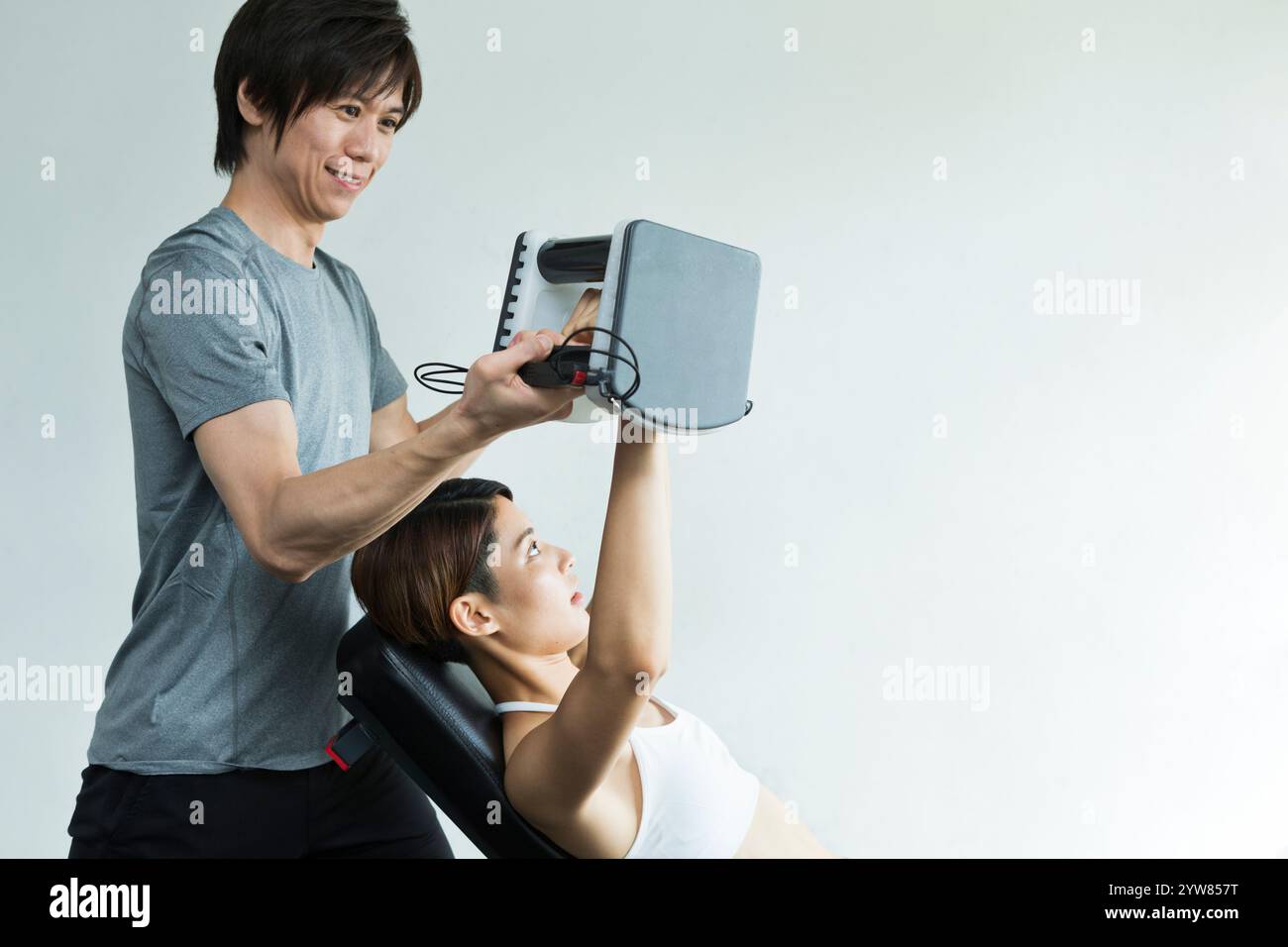 Jeune femme s'entraînant au gymnase avec entraîneur Banque D'Images