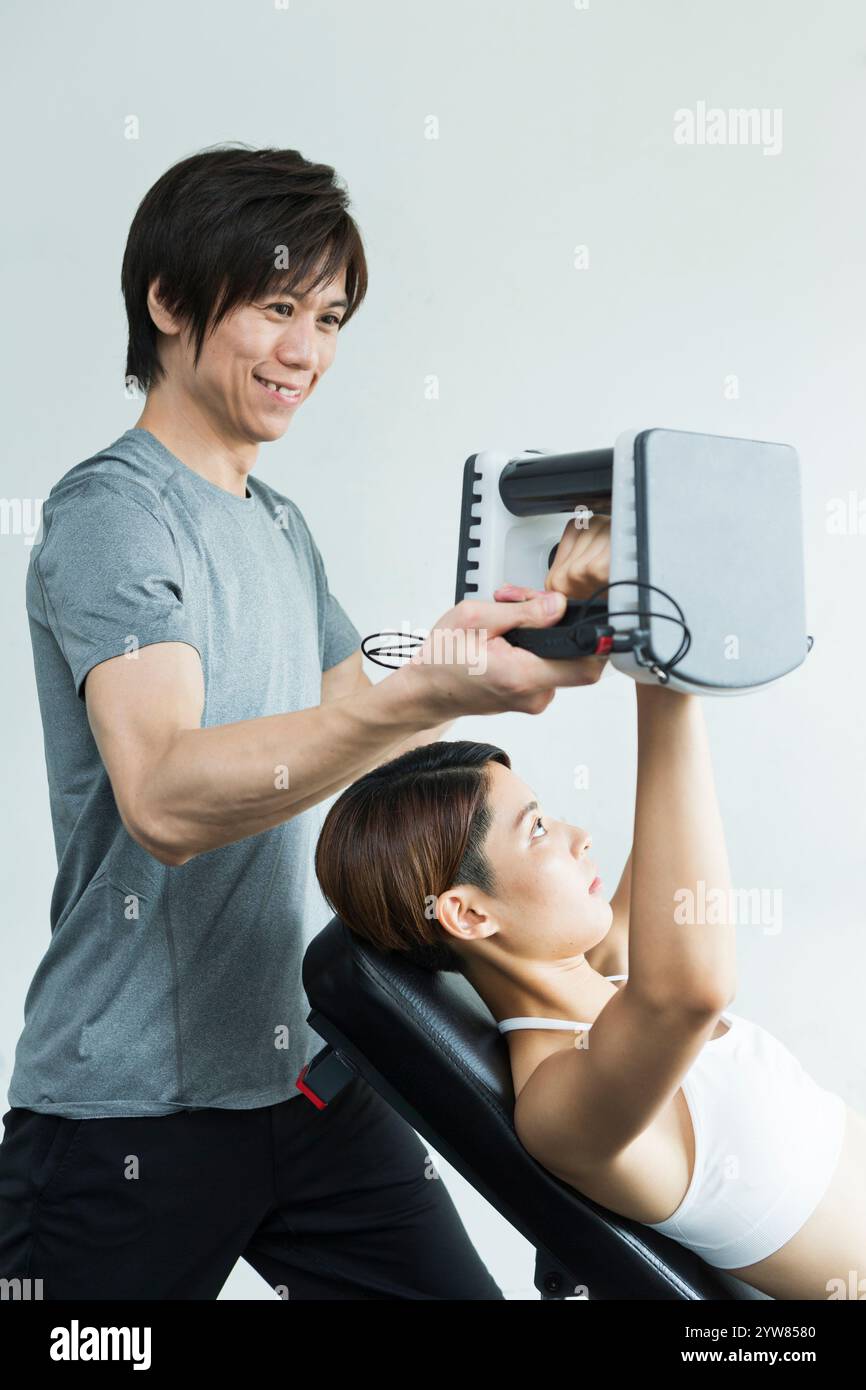 Jeune femme s'entraînant au gymnase avec entraîneur Banque D'Images