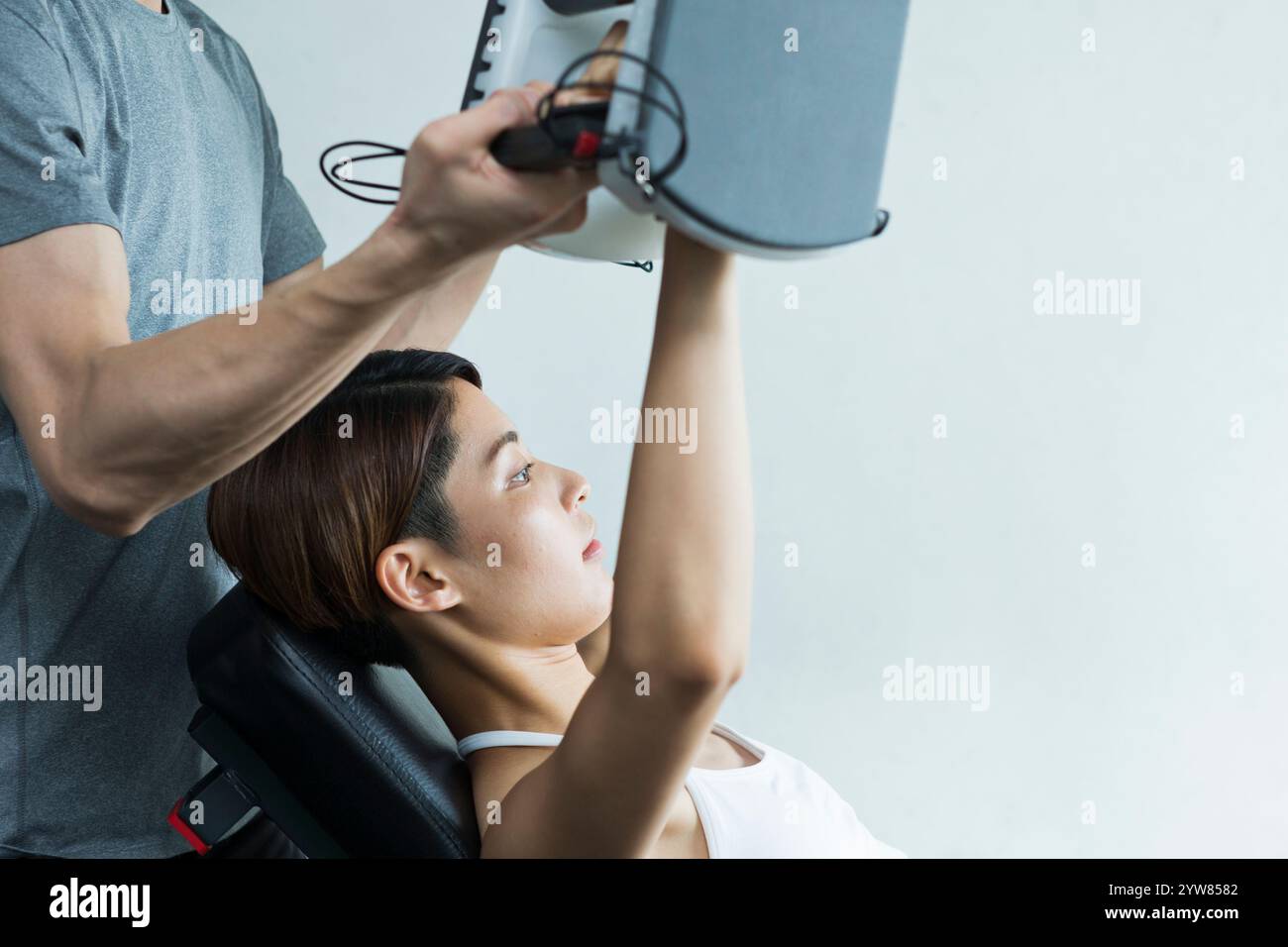 Jeune femme s'entraînant au gymnase avec entraîneur Banque D'Images