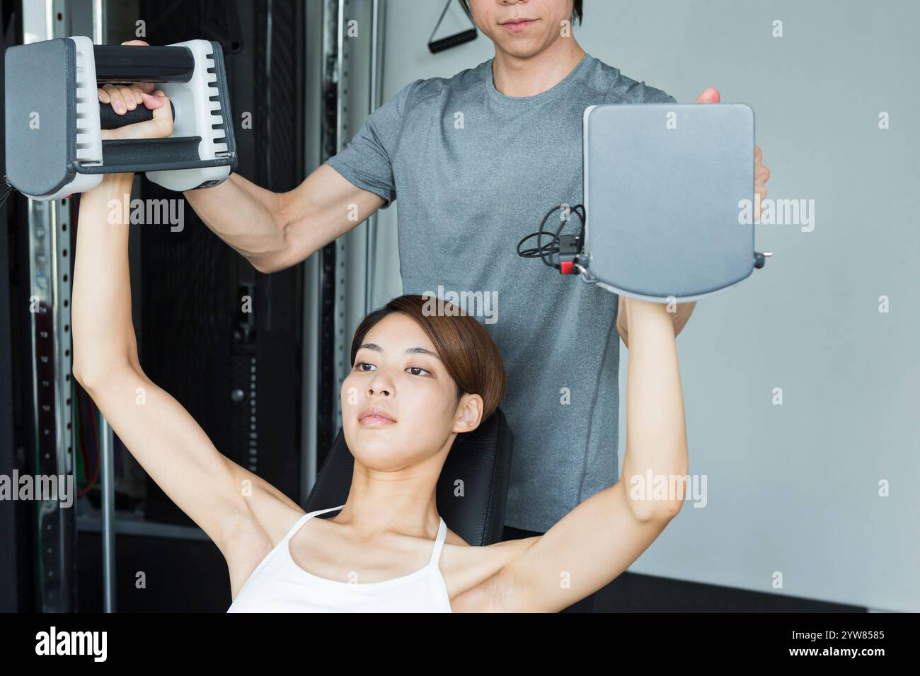 Jeune femme s'entraînant au gymnase avec entraîneur Banque D'Images