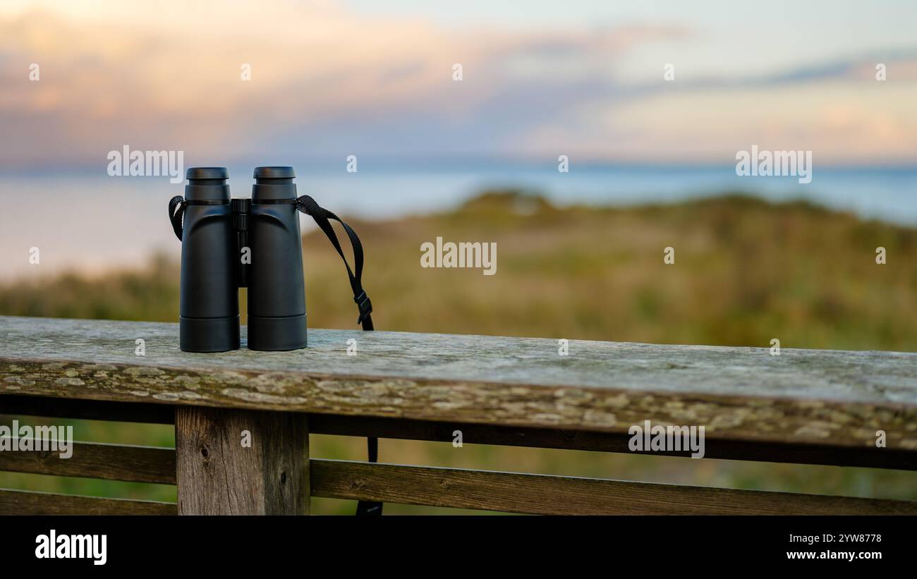 Jumelles noires sur une balustrade en bois surplombant la côte à Sunset for Wildlife and Seascape Viewing Banque D'Images
