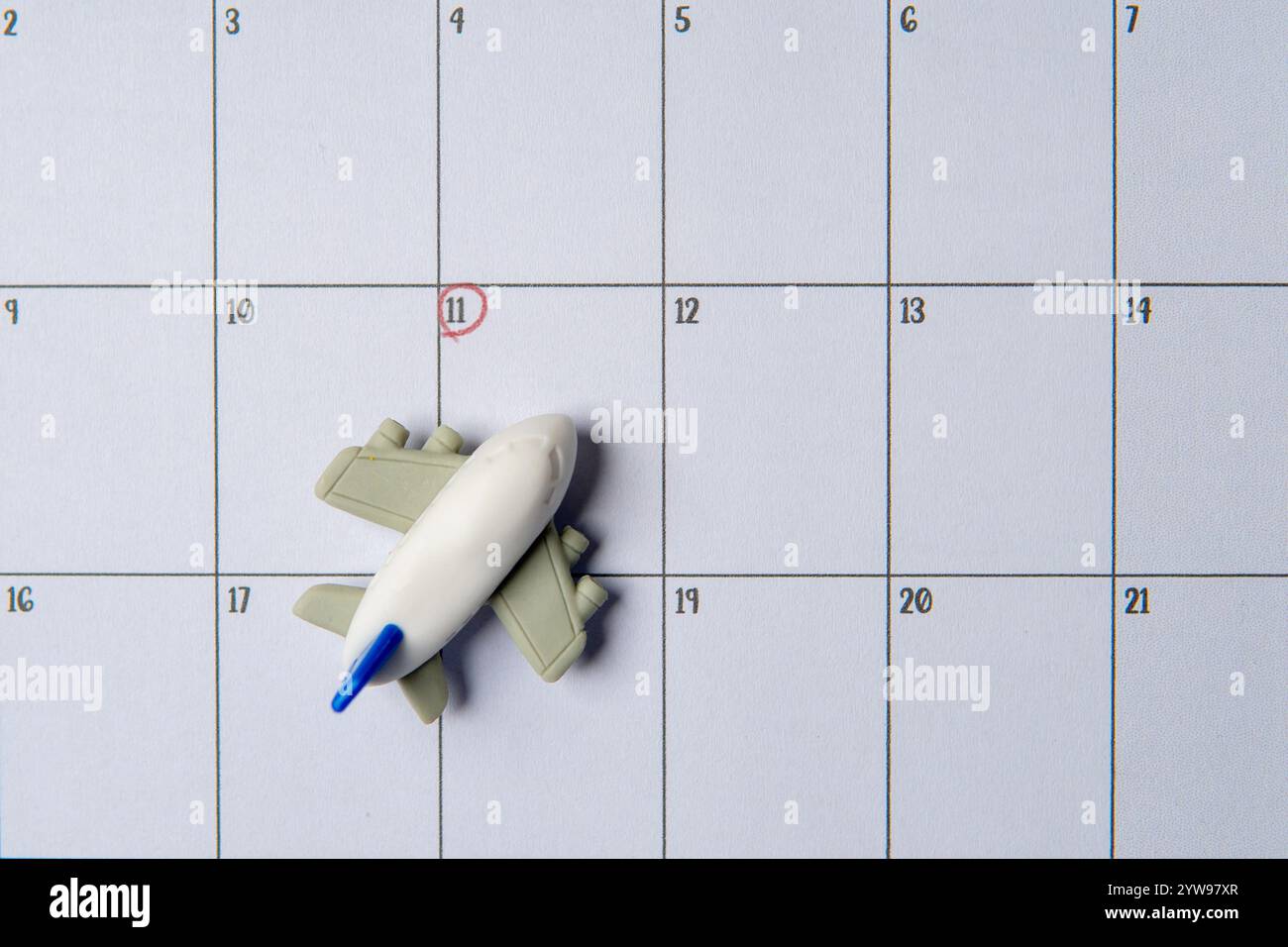 Un jouet avion miniature placé sur un calendrier avec la date entourée en rouge. Planifier un voyage, dans l'attente de voyager concept. Banque D'Images