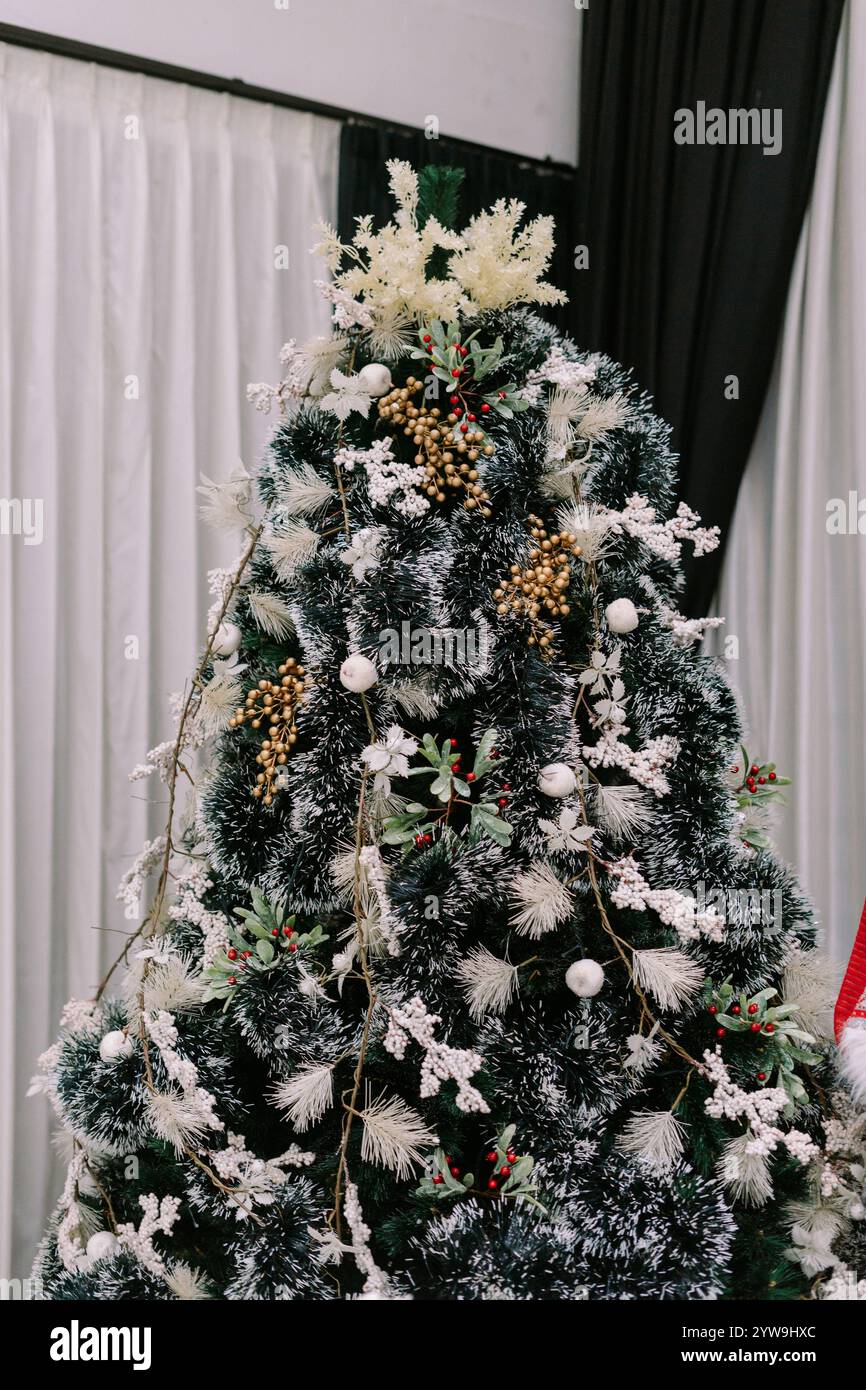 Un sapin de Noël magnifiquement décoré avec des ornements vibrants et des lumières scintillantes, créant une atmosphère festive et joyeuse pour la saison des fêtes Banque D'Images