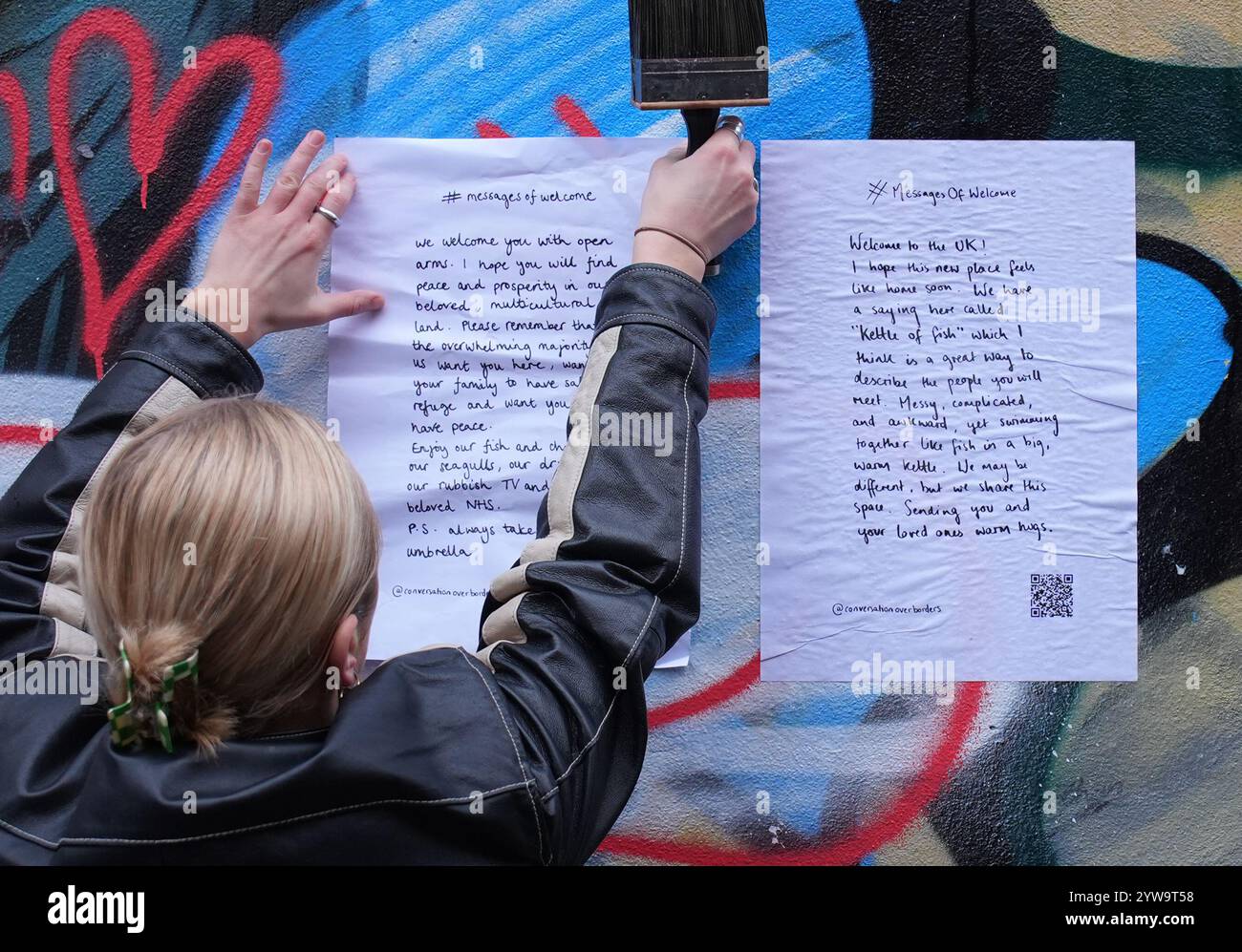 Colette Batten-Turner, PDG de conversation Over Borders, place des affiches avec le message de Noël « Un message de bienvenue » dans la ville de Brighton, dans l'est du Sussex, dans le cadre d'une campagne nationale de l'organisation caritative de réfugiés conversation Over Borders. Des centaines d'affiches présentant des messages manuscrits de compassion envers les demandeurs d'asile sont affichées dans tout le pays à l'approche de Noël dans le cadre d'une campagne nationale visant à créer un «environnement accueillant pour tous» au lendemain des émeutes d'été. Date de la photo : mardi 10 décembre 2024. Banque D'Images