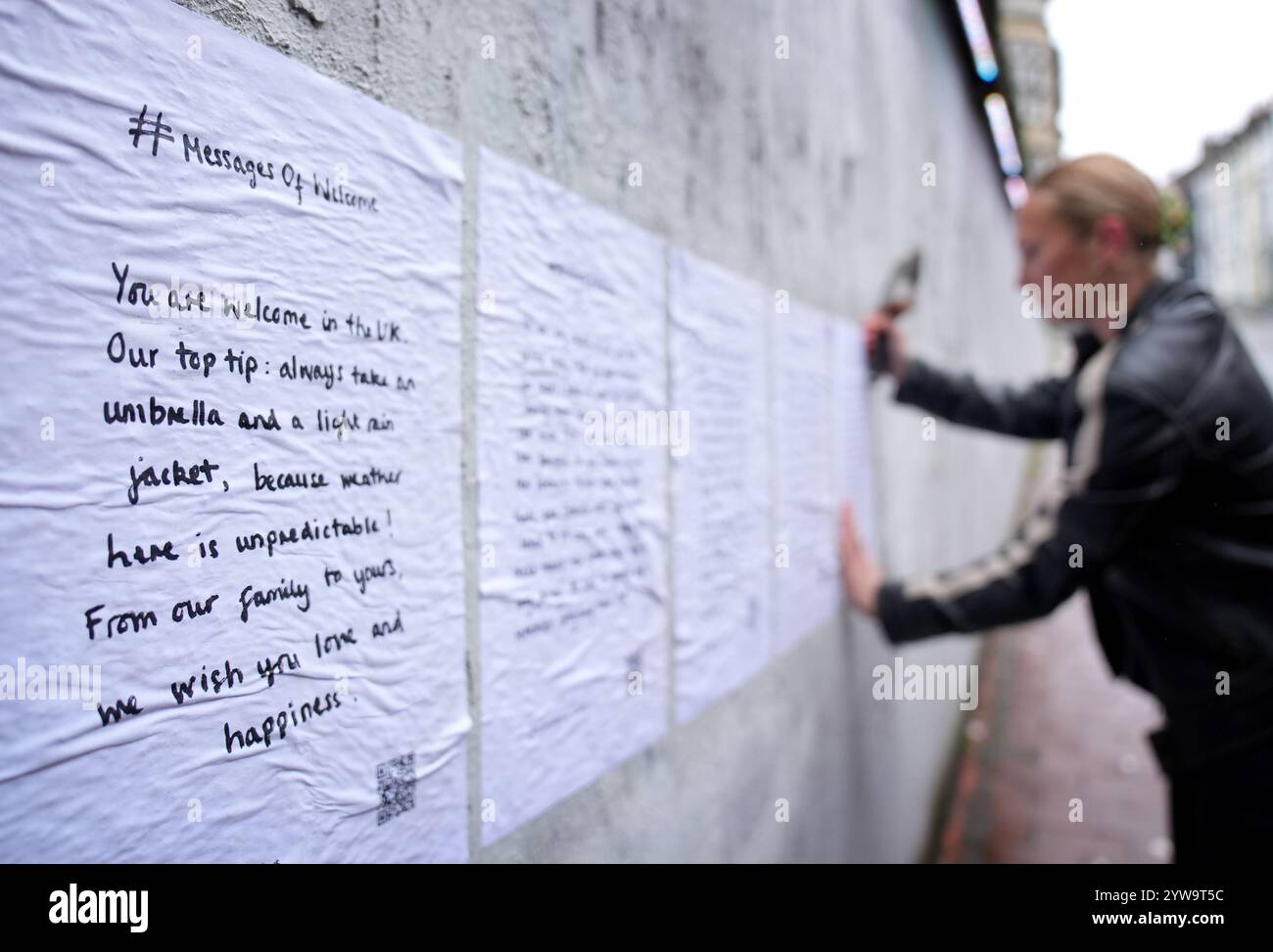 Colette Batten-Turner, PDG de conversation Over Borders, place des affiches avec le message de Noël « Un message de bienvenue » dans la ville de Brighton, dans l'est du Sussex, dans le cadre d'une campagne nationale de l'organisation caritative de réfugiés conversation Over Borders. Des centaines d'affiches présentant des messages manuscrits de compassion envers les demandeurs d'asile sont affichées dans tout le pays à l'approche de Noël dans le cadre d'une campagne nationale visant à créer un «environnement accueillant pour tous» au lendemain des émeutes d'été. Date de la photo : mardi 10 décembre 2024. Banque D'Images