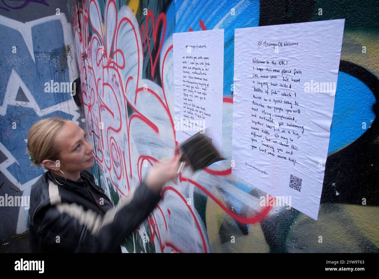 Colette Batten-Turner, PDG de conversation Over Borders, place des affiches avec le message de Noël « Un message de bienvenue » dans la ville de Brighton, dans l'est du Sussex, dans le cadre d'une campagne nationale de l'organisation caritative de réfugiés conversation Over Borders. Des centaines d'affiches présentant des messages manuscrits de compassion envers les demandeurs d'asile sont affichées dans tout le pays à l'approche de Noël dans le cadre d'une campagne nationale visant à créer un «environnement accueillant pour tous» au lendemain des émeutes d'été. Date de la photo : mardi 10 décembre 2024. Banque D'Images