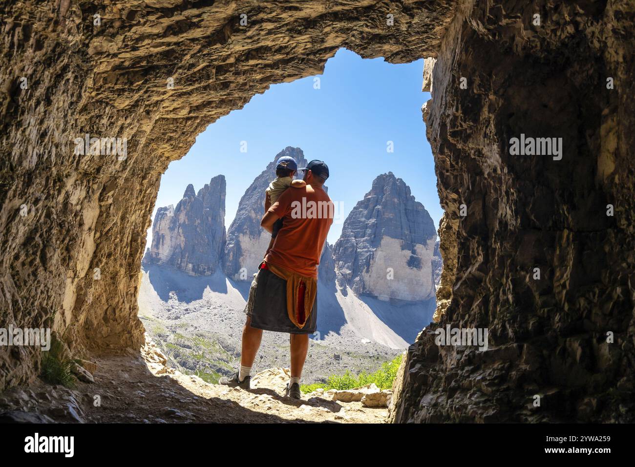 Père tenant son fils admirant la tre cime di lavaredo, dolomites, d'une grotte de Tre Cime lors d'une randonnée estivale Banque D'Images