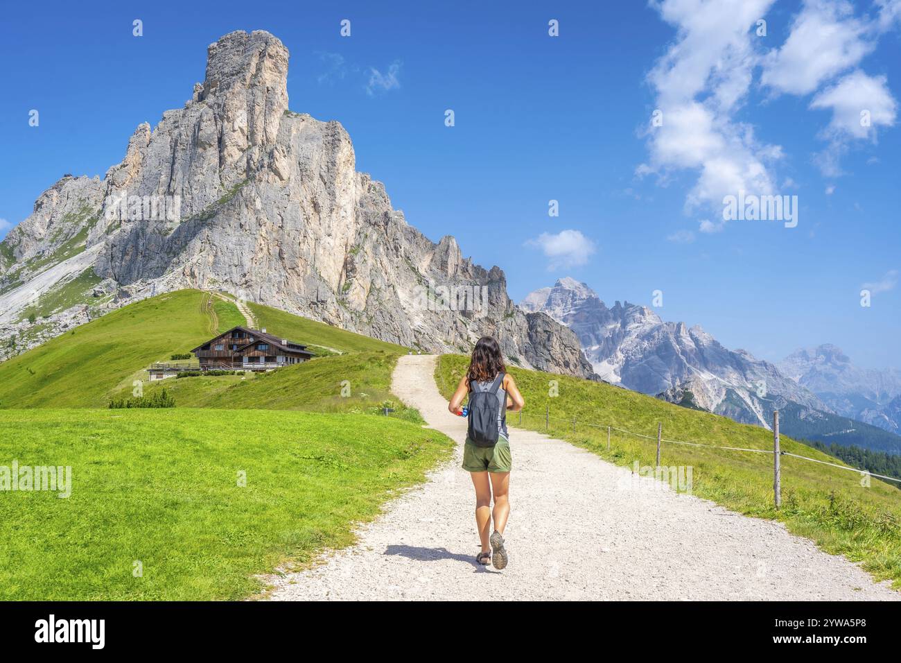 Touriste femme marchant sur un chemin de gravier profitant de la vue sur le pic nuvolau et l'abri de montagne près du col de giau dans les dolomites italiennes Banque D'Images