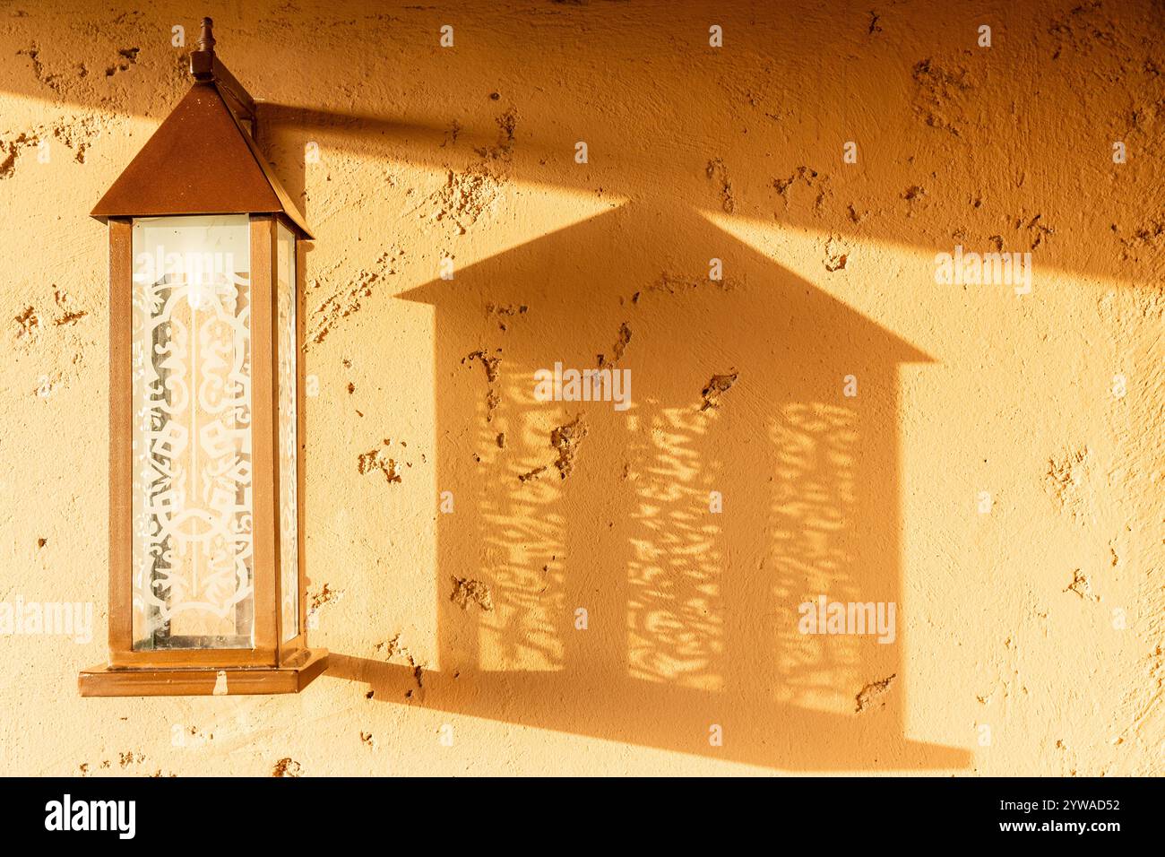Une applique, éclairée par un soleil bas, projette son ombre sur un mur Banque D'Images