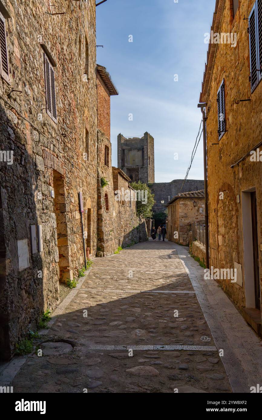 Une étroite rue pavée dans la ville médiévale fortifiée de Monteriggioni, province de Sienne, Italie. Banque D'Images