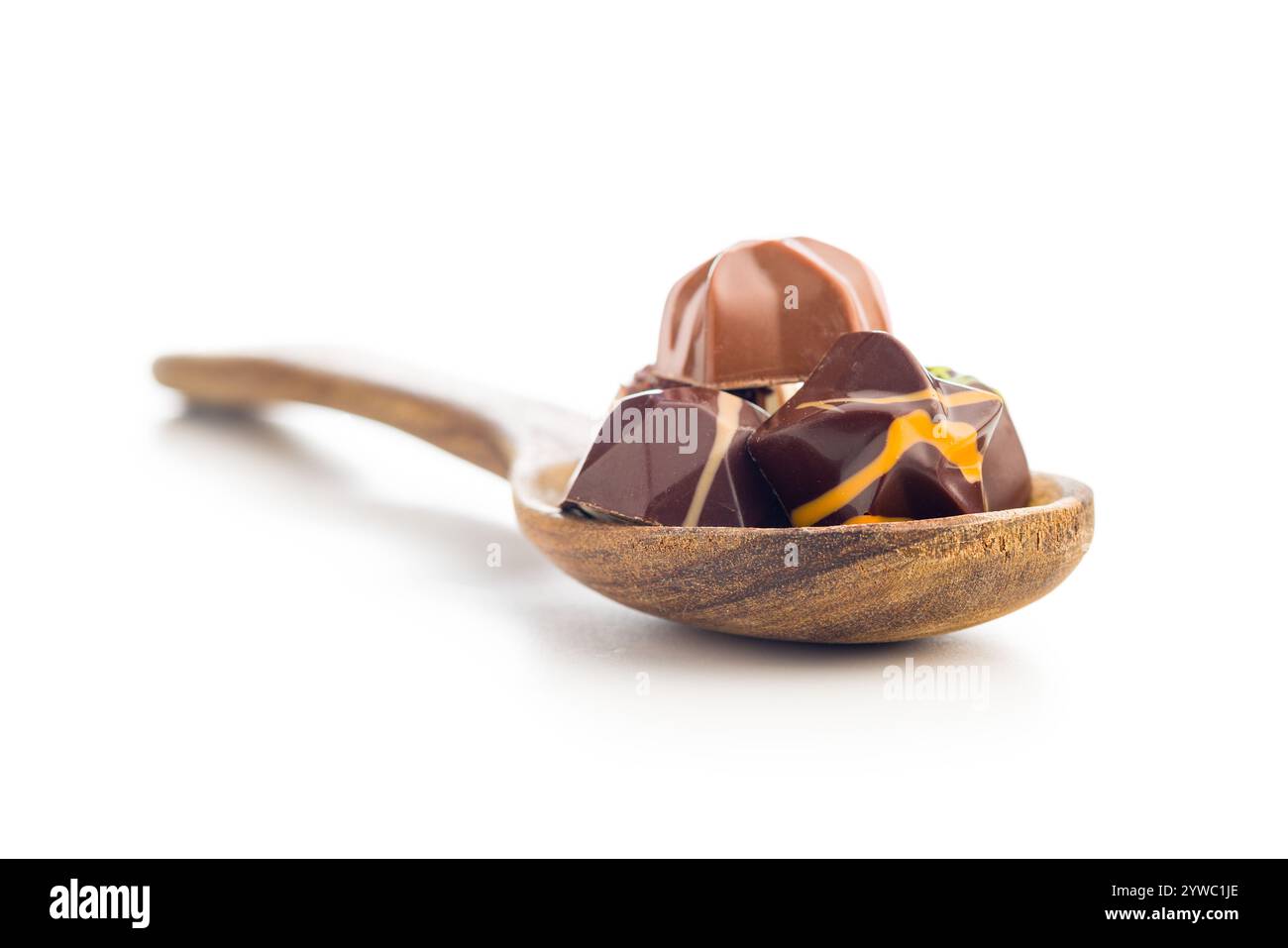 Mélange de pralines au chocolat sur cuillère isolé sur fond blanc. Banque D'Images