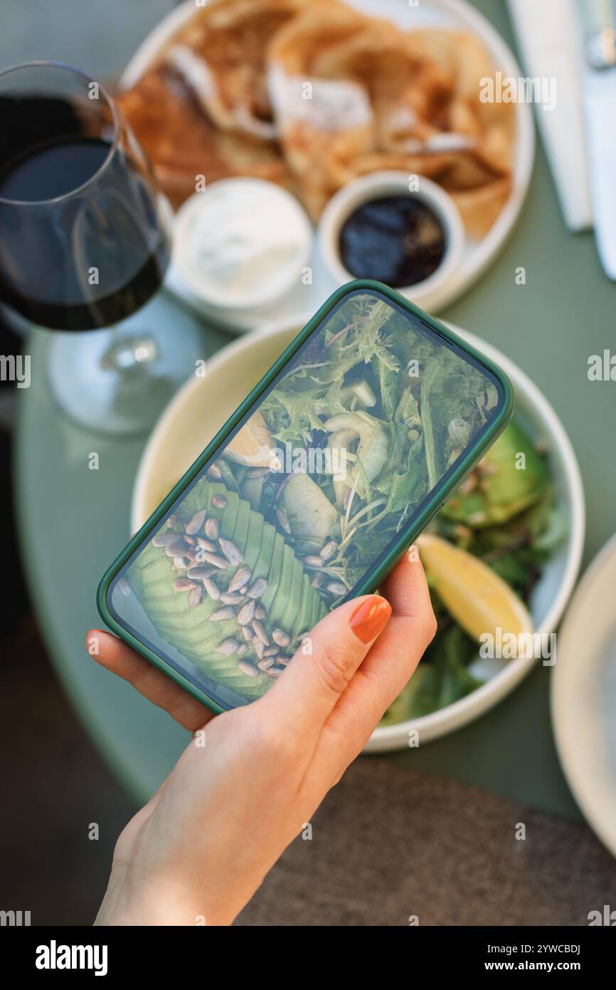 Vue aérienne d'une femme prenant une photo de son déjeuner de salade d'avocat sur son téléphone portable Banque D'Images