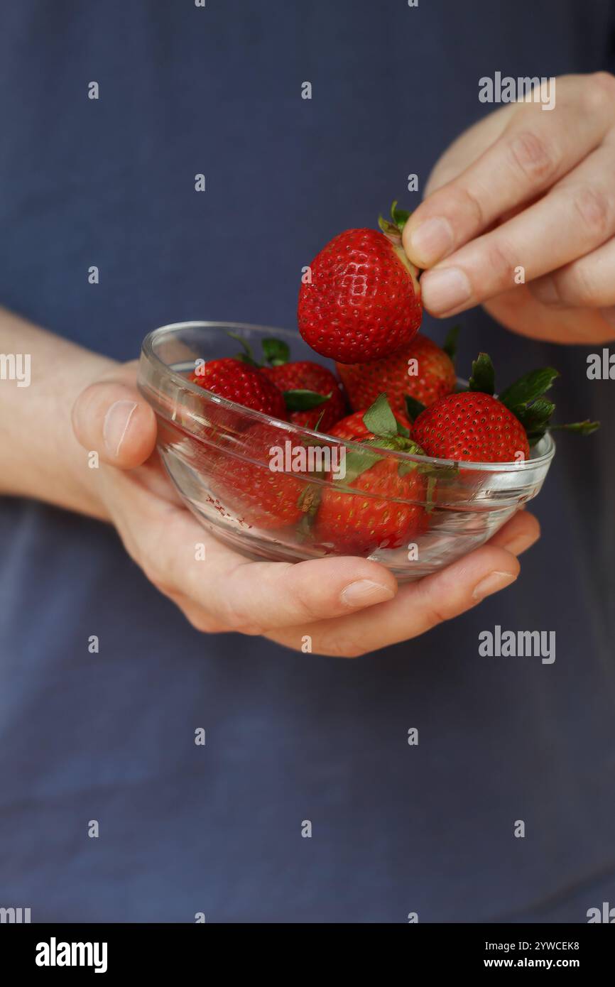 Gros plan de main masculine caucasienne tenant un bol de fraises Banque D'Images