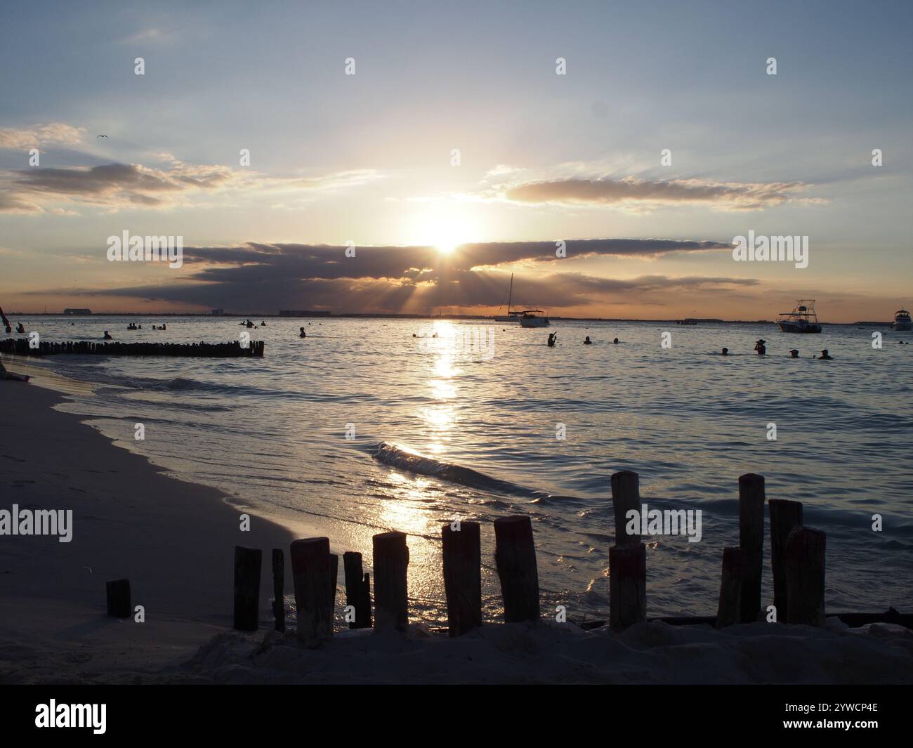 Coucher de soleil à Playa Norte, Isla Mujeres, Quintana Roo, Mexique avec des gens nageant dans l'océan. Concept : vacances tropicales, vacances de rêve Banque D'Images