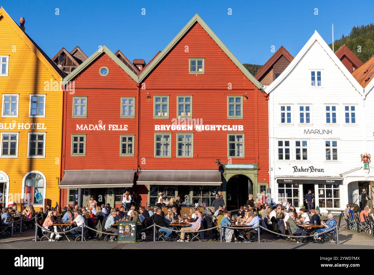 Site classé au patrimoine mondial de l'UNESCO de Bryggen à Bergen avec des bars et des pubs accueillant des amis socialisant à l'extérieur Banque D'Images