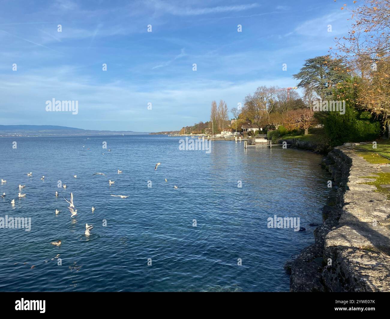 Beau coucher de soleil sur des eaux calmes avec une jetée en bois et des montagnes lointaines sur une journée paisible - Image de stock capturée avec un smartphone