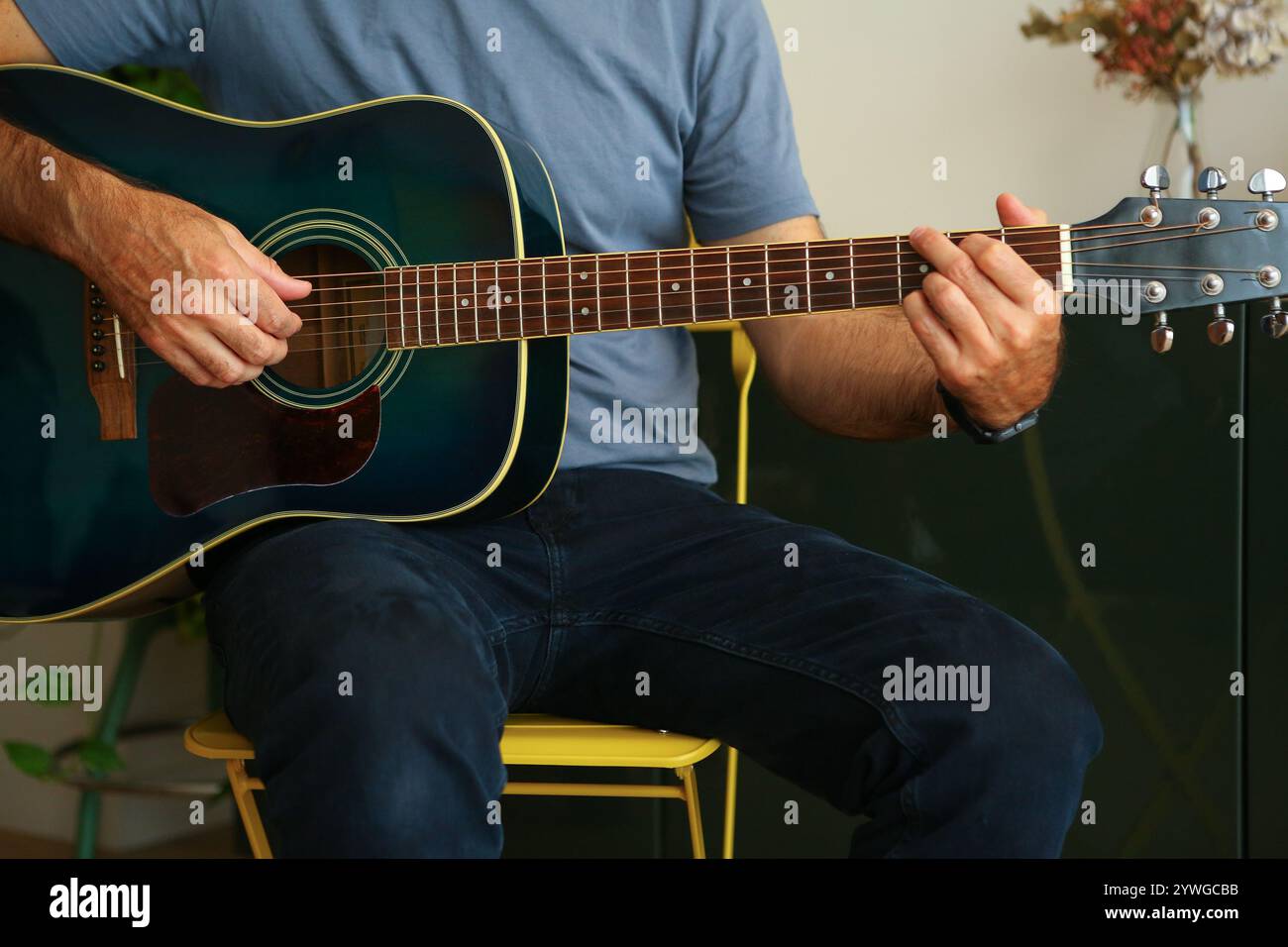 Gros plan des mains d'un homme jouant un accord G à la guitare acoustique à la maison Banque D'Images