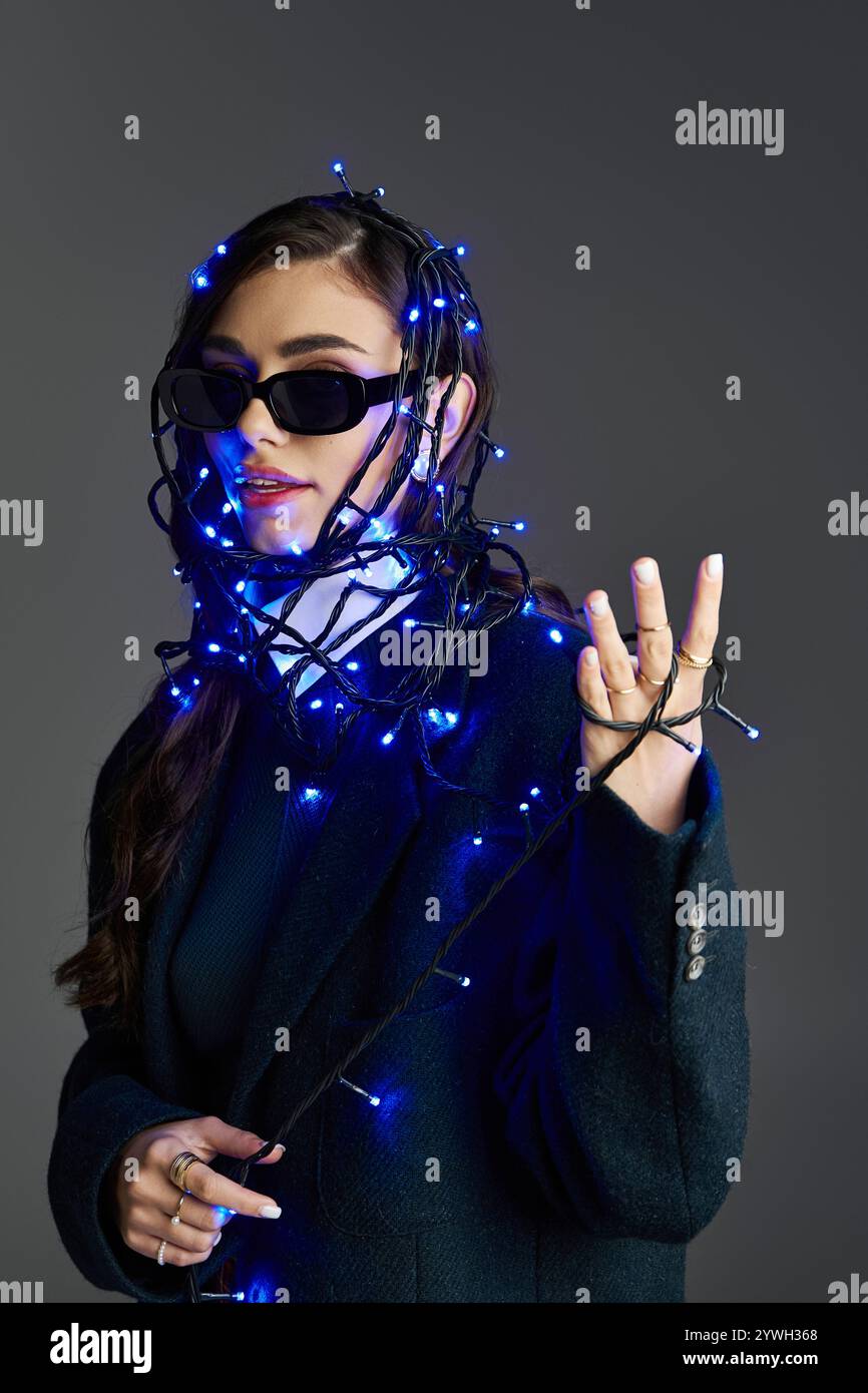 Jolie jeune femme enveloppée dans des lumières bleues présente une déclaration de mode unique dans le cadre de studio. Banque D'Images