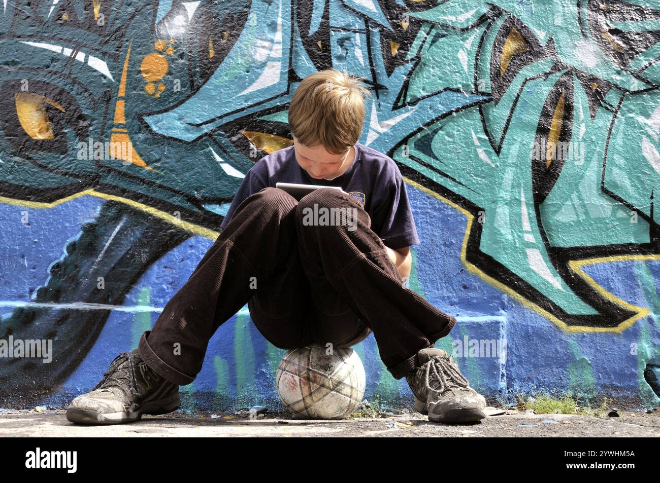 Garçon de dix ans jouant avec sa Nintendo devant un mur de graffitis, terrain de football, Allemagne, Europe Banque D'Images Garçon de dix ans jouant avec sa Nintendo devant un mur de graffitis, terrain de football, Allemagne, Europe Banque D'Images