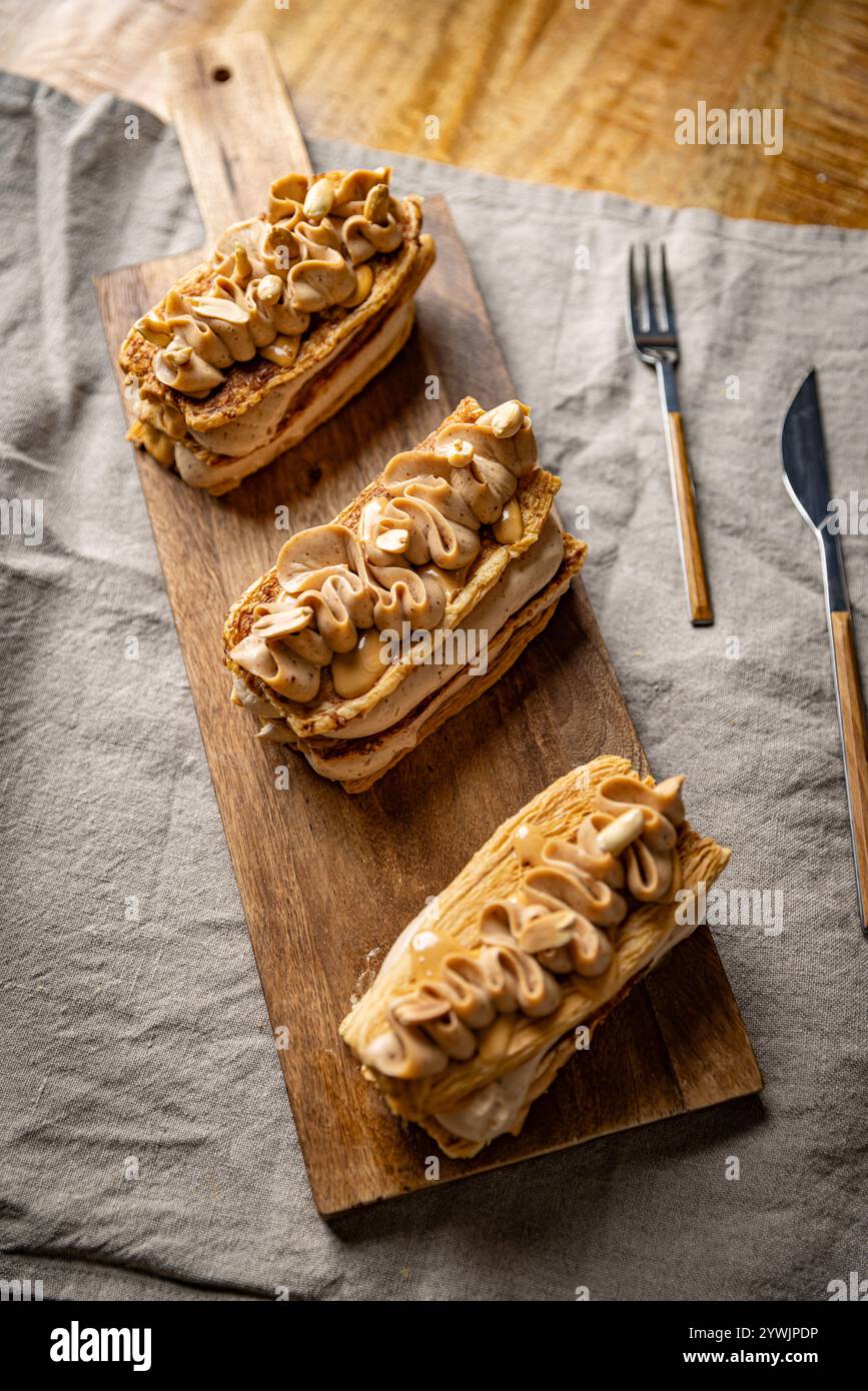 Délicieuses pâtisseries de mille feuilles avec garniture de crème de beurre d'arachide reposant sur une planche de bois Banque D'Images