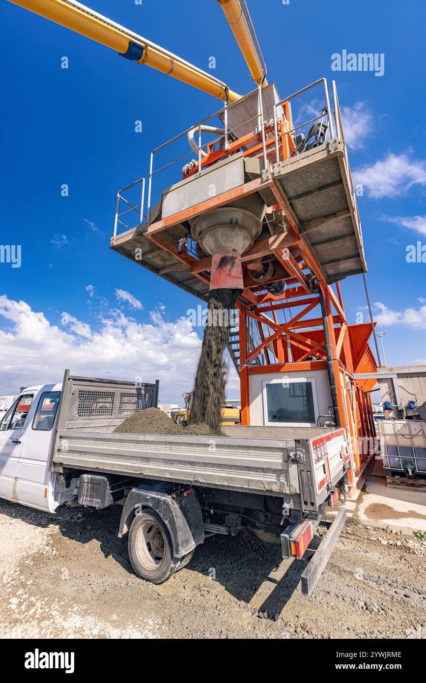 Usine de mélange d'asphalte chargeant le mélange d'asphalte dans la plate-forme du camion sur le chantier de construction Banque D'Images