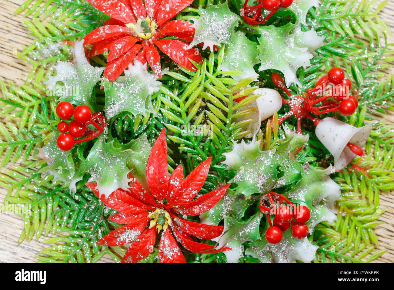gros plan des années 1960 vintage en plastique couronne de noël table décoration de pièce maîtresse avec fleurs de noël houx et feuillage Banque D'Images