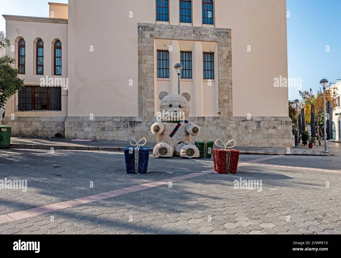 Un grand ours en peluche habillé de rubans de Noël et de grandes boîtes emballées dans la rue dans l'île de Kos, en Grèce. Banque D'Images