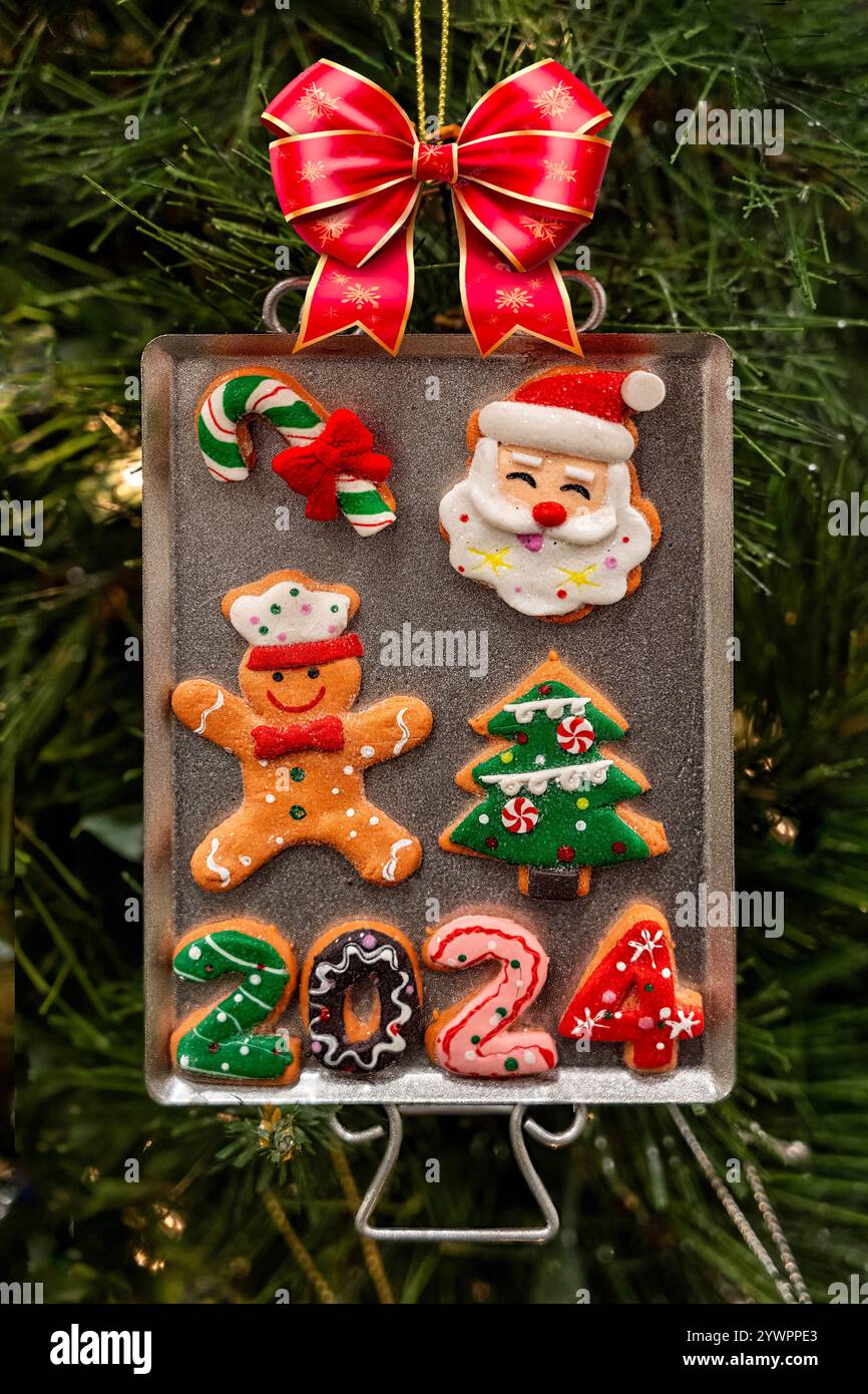 Plateau à biscuits orament de Noël avec arc, canne à bonbons, père noël, homme en pain d'épices et date sur fond de pin vert Banque D'Images