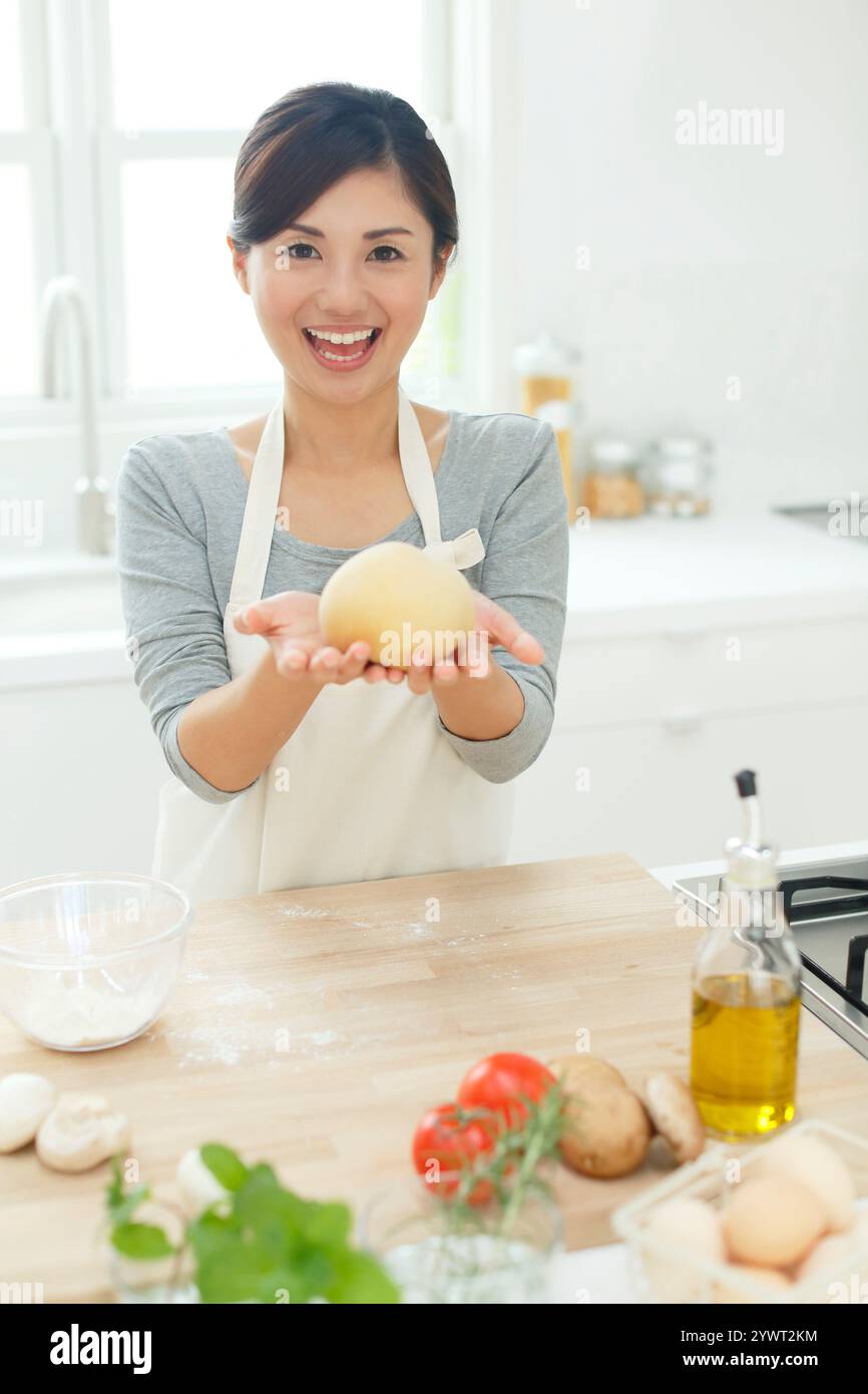 Femme cuisinant dans une cuisine lumineuse Banque D'Images