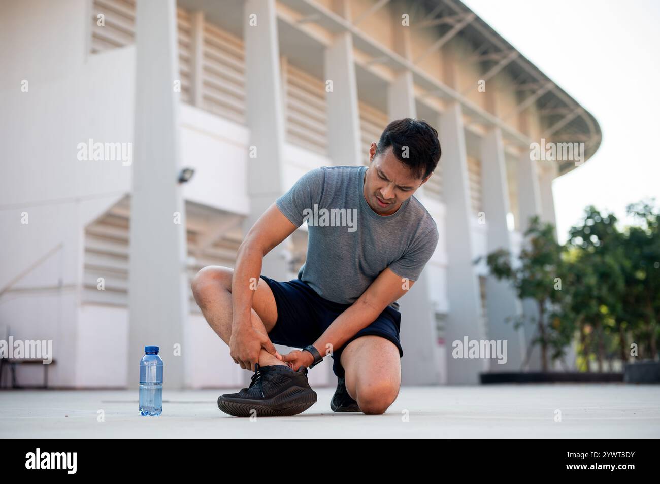 Un homme asiatique en vêtements de sport souffre d'une entorse à la cheville en courant à l'extérieur. soins de santé et concepts sportifs Banque D'Images