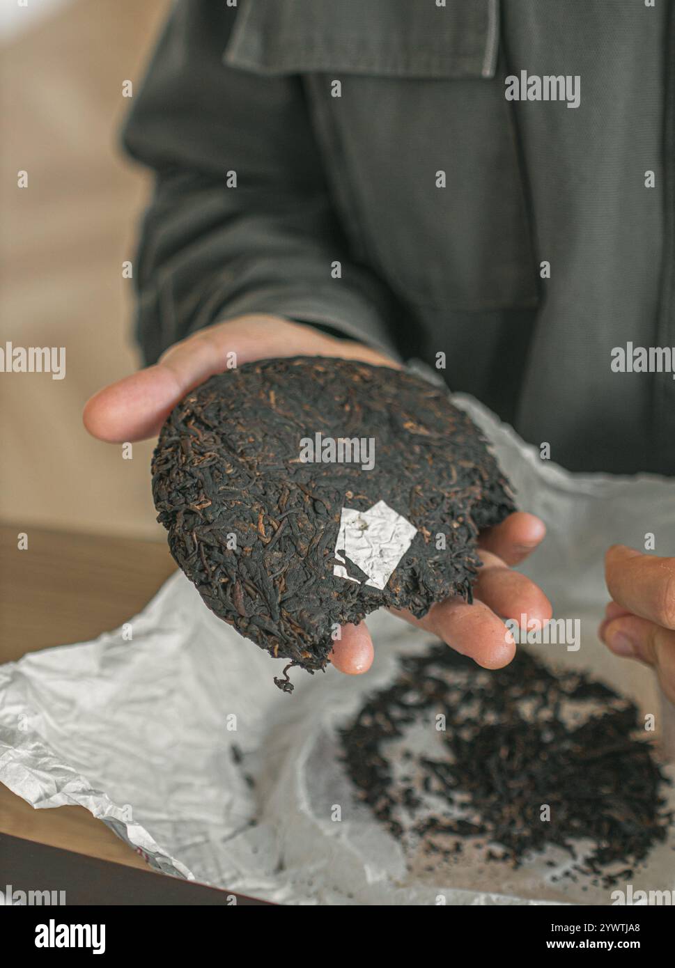 Un gâteau de thé traditionnel placé délicatement dans la main à côté de feuilles libres fraîches pour le brassage Banque D'Images