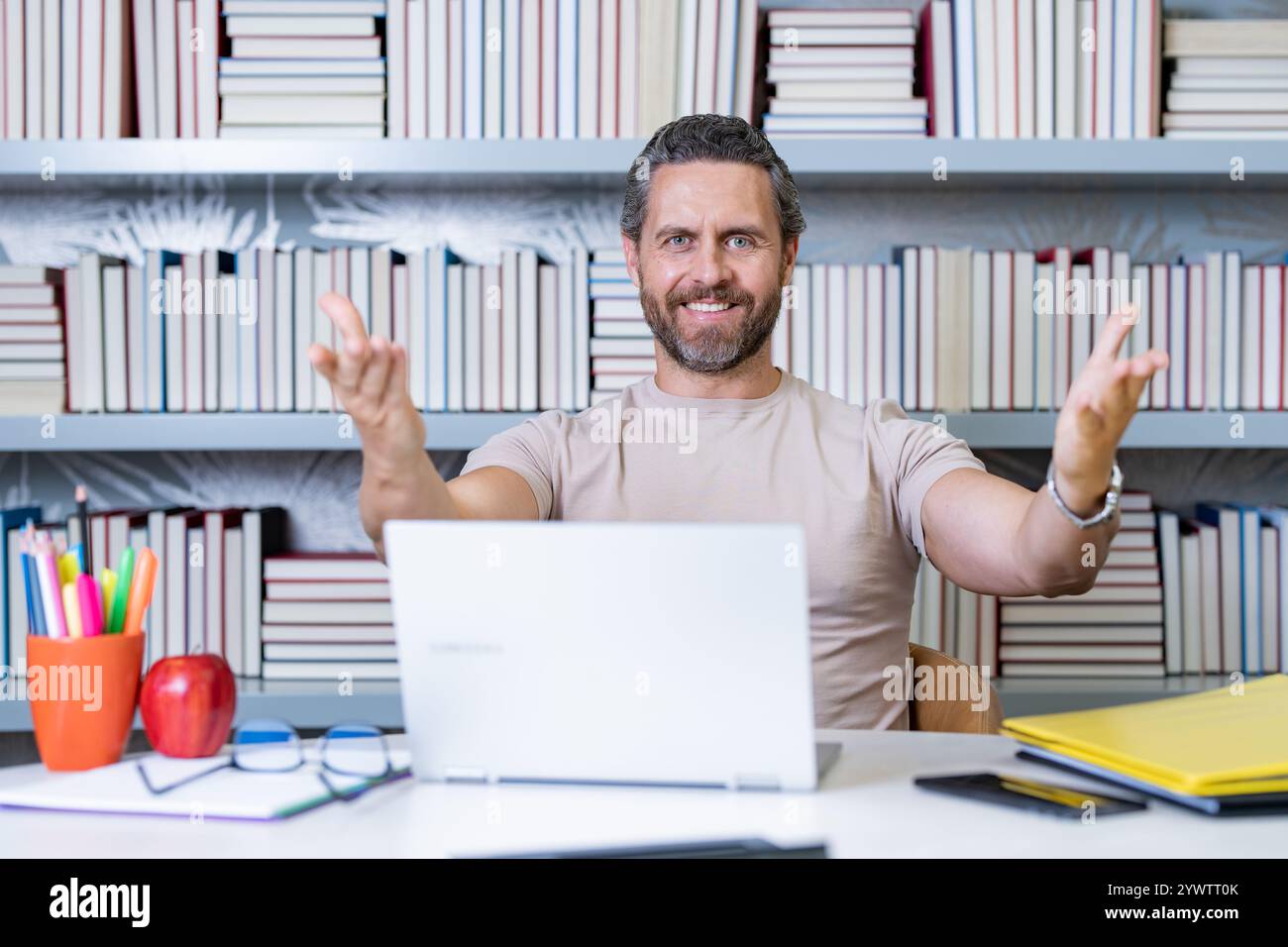 Journée des enseignants. Bon professeur avec un ordinateur portable dans la salle de classe. Connaissance et éducation avec un enseignant d'âge moyen. Professeur hispanique avec livre. Enseignant Banque D'Images