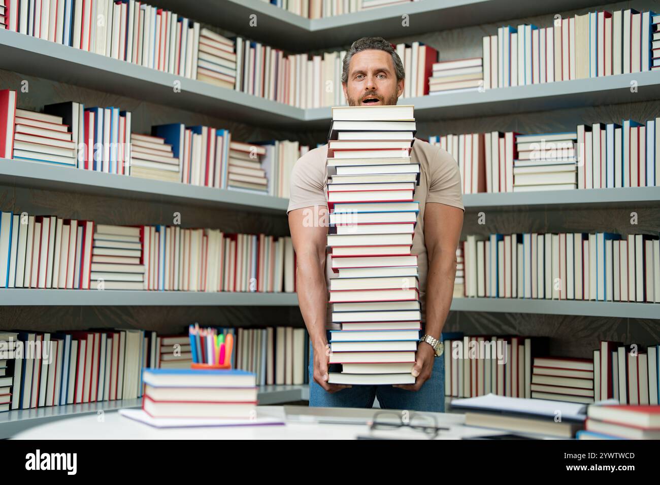 Drôle d'enseignant de tenir beaucoup de livres. Professeur fou avec des livres. Enseignant enthousiaste dans la bibliothèque de livres de l'école. Examen universitaire. Étudier enseigner à l'université. Éducateur Banque D'Images