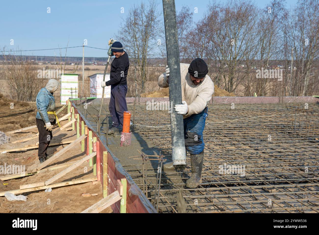 RÉGION DE LENINGRAD, RUSSIE - 28 MARS 2021 : les travailleurs migrants de la construction versent la fondation d'une maison de campagne un jour ensoleillé de mars Banque D'Images