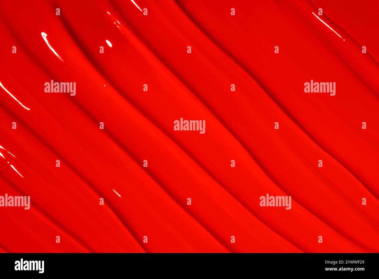 Texture de rouge à lèvres rouge avec des lignes couvrant toute l'image. Fond cosmétique audacieux, couleur vibrante. Banque D'Images