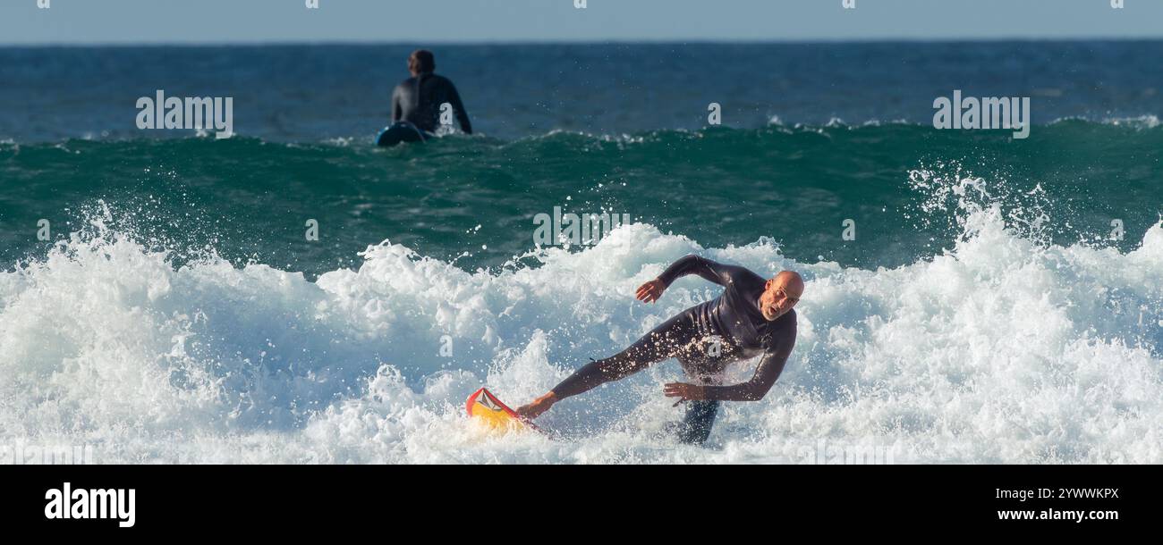 Une image panoramique d'un surfeur masculin mature s'effondrant sur une vague à Fistral à Newquay en Cornouailles au Royaume-Uni en Europe Banque D'Images Une image panoramique d'un surfeur masculin mature s'effondrant sur une vague à Fistral à Newquay en Cornouailles au Royaume-Uni en Europe Banque D'Images