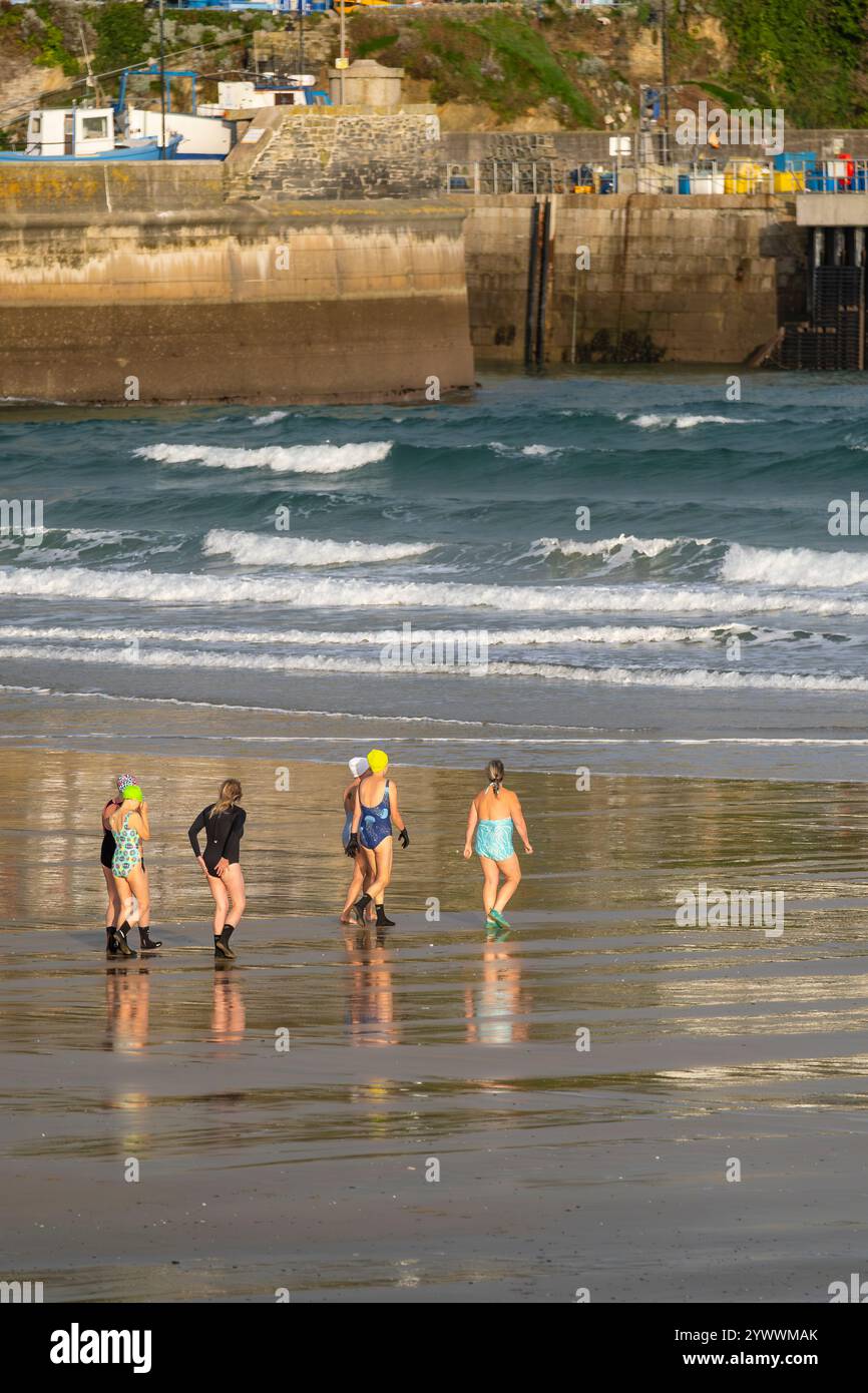 Un groupe de femmes nageuses d'eau froide marchant vers la mer pour une baignade tôt le matin à Towan Beach à Newquay Cornwall Royaume-Uni. Banque D'Images